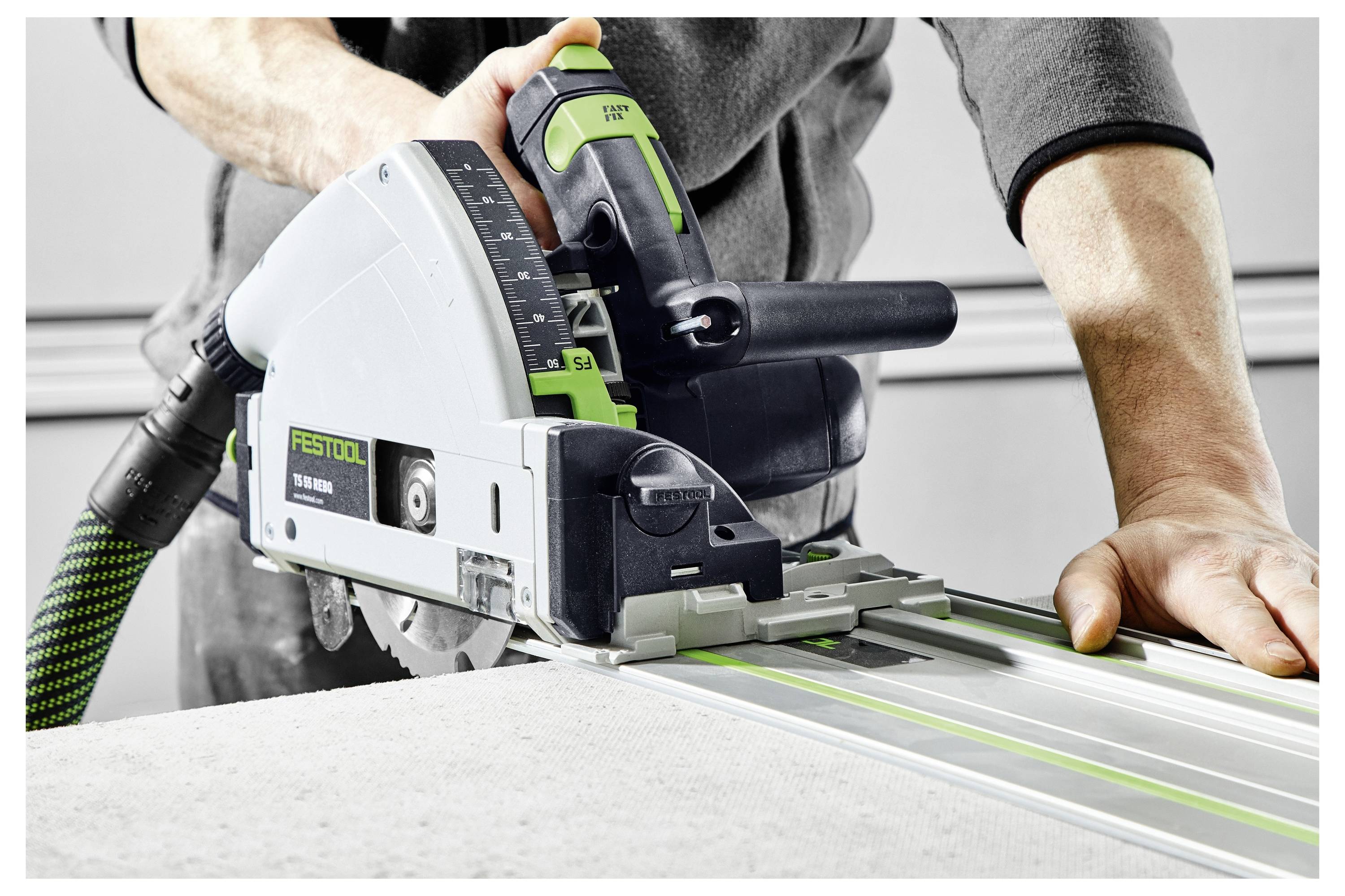 Eine Person benutzt eine Festool-Tauchkreissäge, um ein Brett zu schneiden, wobei sie das präzise Schneiden mit einem geführten Schienensystem in einer Werkstattumgebung demonstriert.