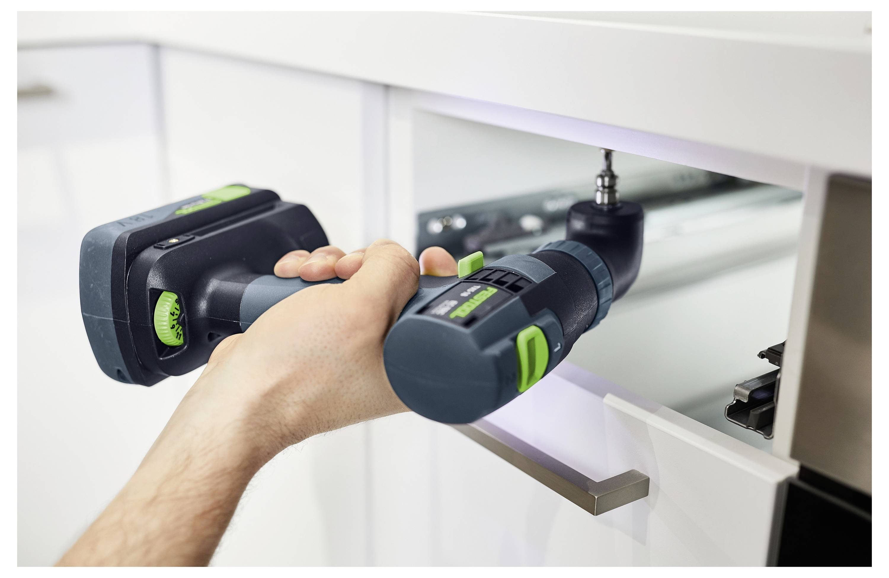 Eine Person verwendet einen Elektroschrauber, um eine Schraube in eine Küchenschublade einzubauen, um eine DIY-Heimwerkeraufgabe zu demonstrieren.