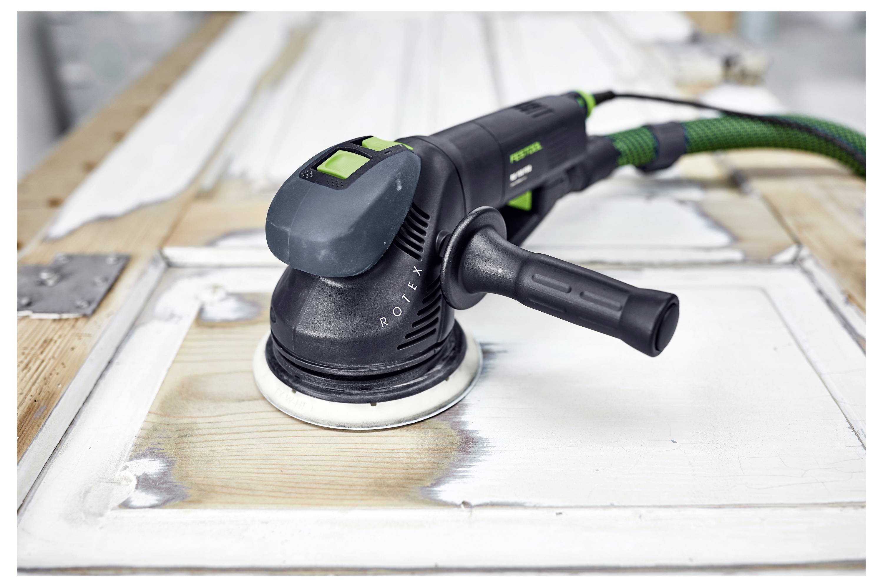 Ein elektrischer Schleiffer, der die Oberfläche einer Holztür glättet und die aufgearbeiteten Bereiche hervorhebt.