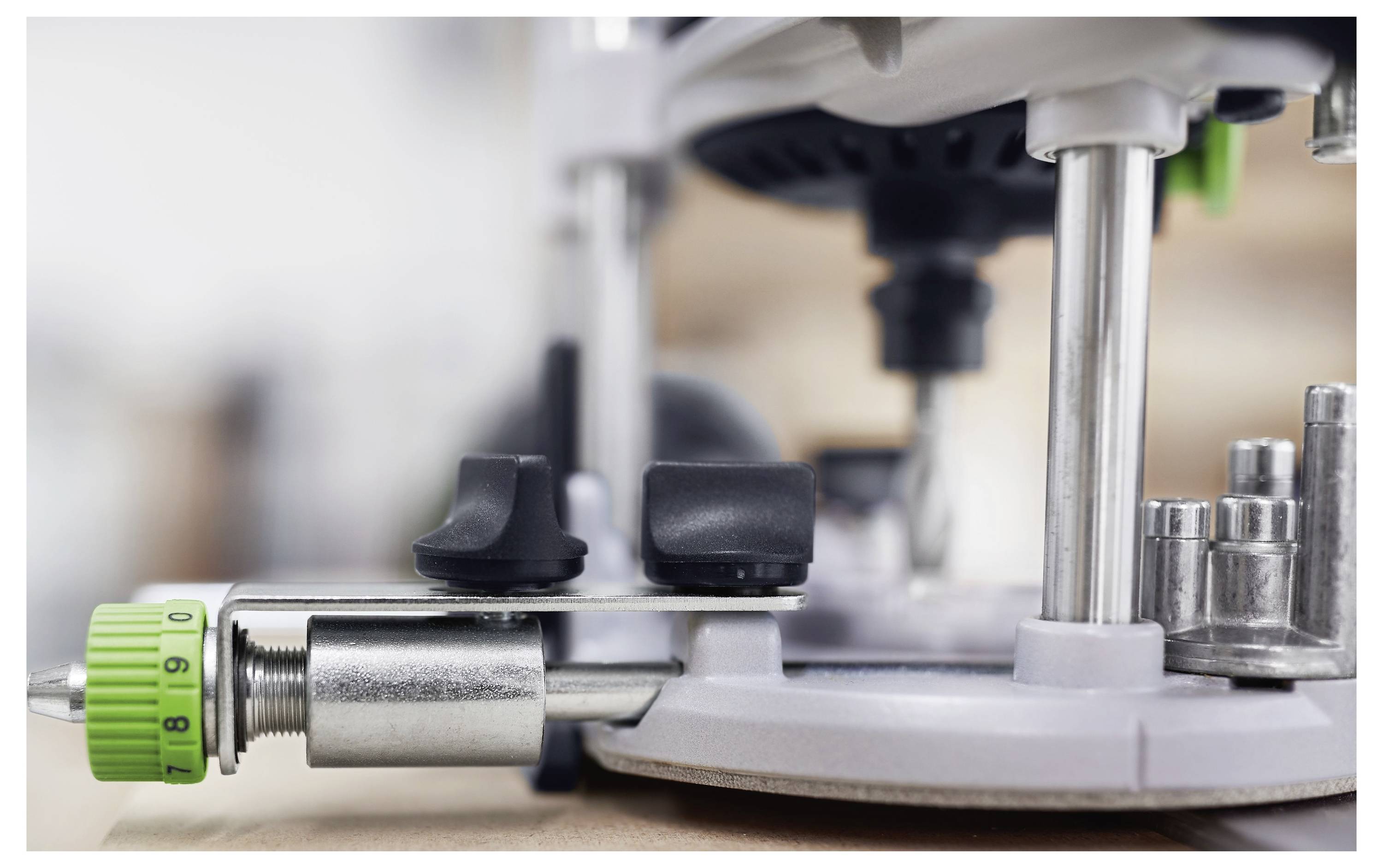 Nahaufnahme eines Fräswerkzeugsatzes mit einem grünen Drehknopf zur Einstellung der Einstellungen, konzentriert auf seine mechanischen Komponenten auf einer Holzoberfläche.