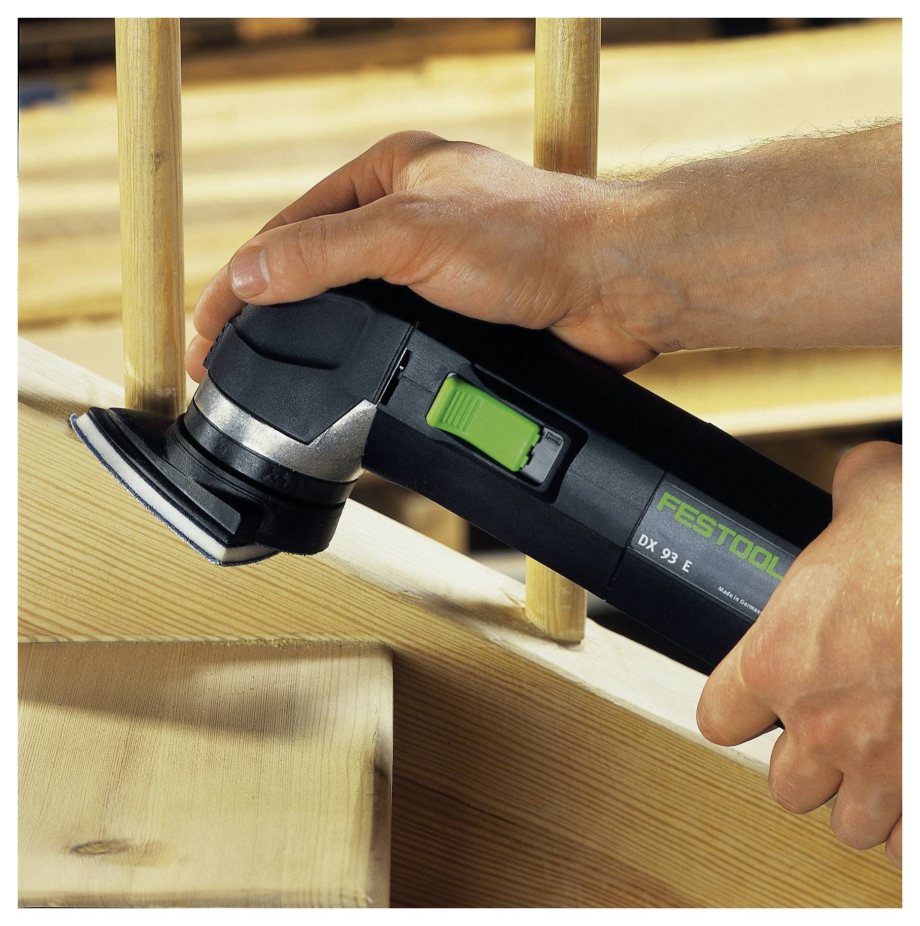 Eine Person benutzt einen Festool DX 93 E Schleiffer auf einem hölzernen Handlauf und glättet die Oberfläche für eine polierte Oberfläche.