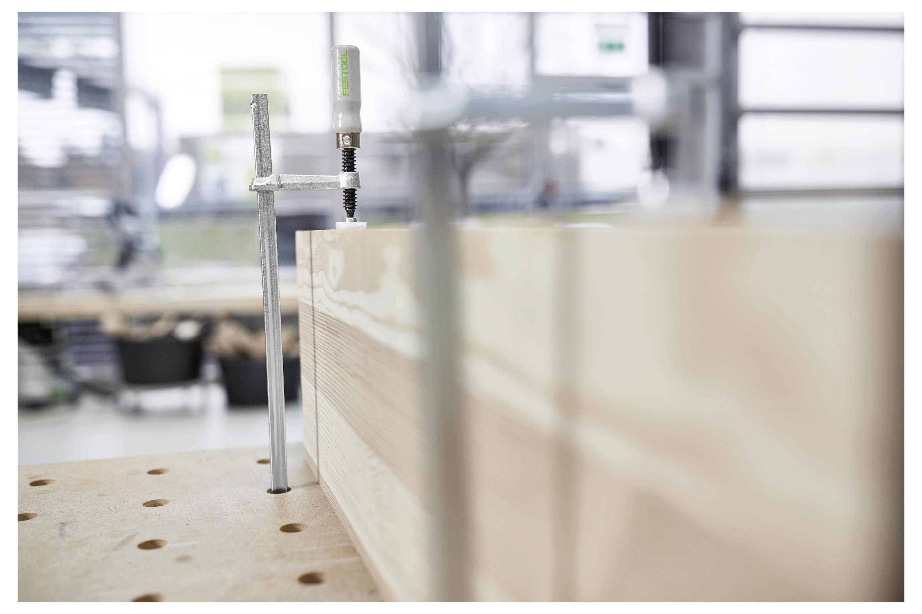 Eine Person in Arbeitskleidung nutzt ein Elektrowerkzeug, um Material in einem großen Behälter auf einer Baustelle mit freiliegenden Ziegelmauern zu mischen.