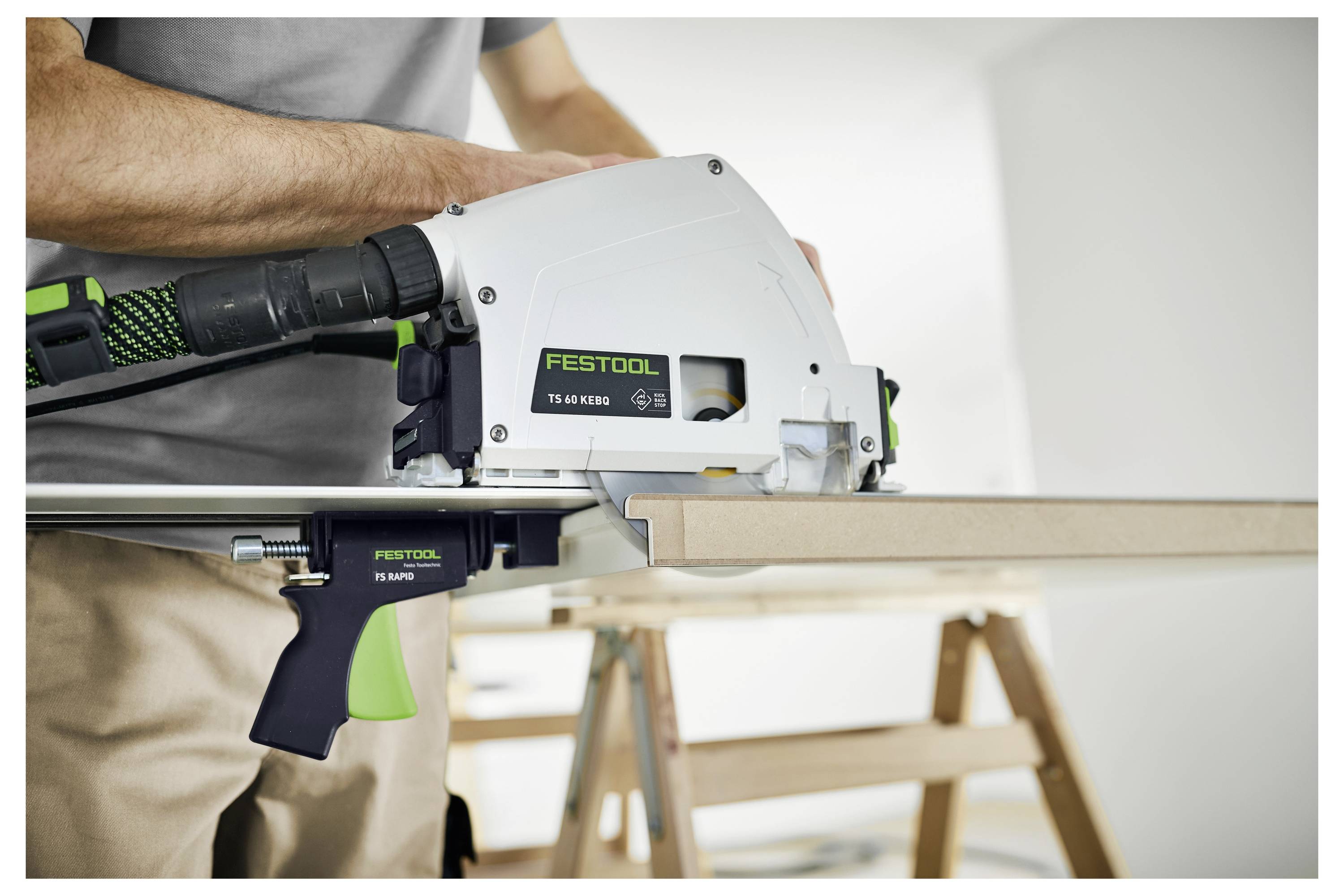 Ein schwarz-grüner Festool-Bandschleifer mit angebrachtem Staubabsaugschlauch, der sein kompaktes Design und die Markenbezeichnung an der Seite zeigt.