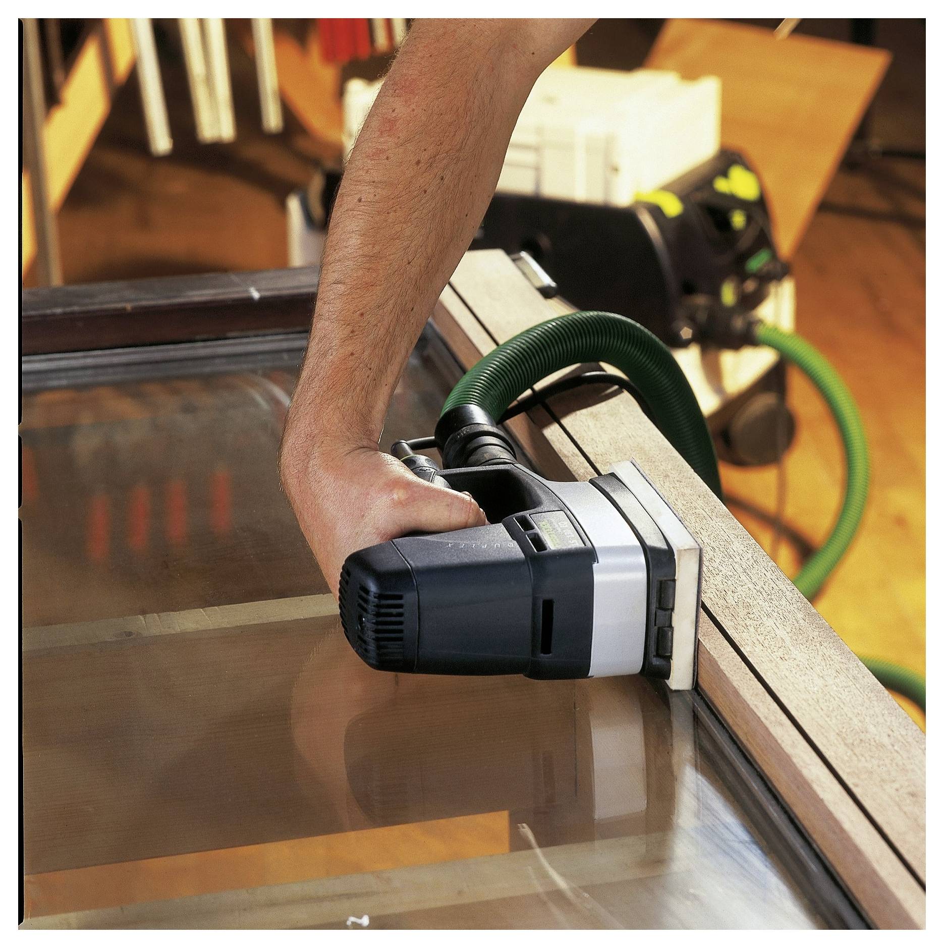 „Nahaufnahme eines Oberfräsers auf einer Holzoberfläche, fokussiert auf das scharfe Fräswerkzeug und die Spannvorrichtungen; verwendet zum Fräsen von Nuten in Holzarbeiten.