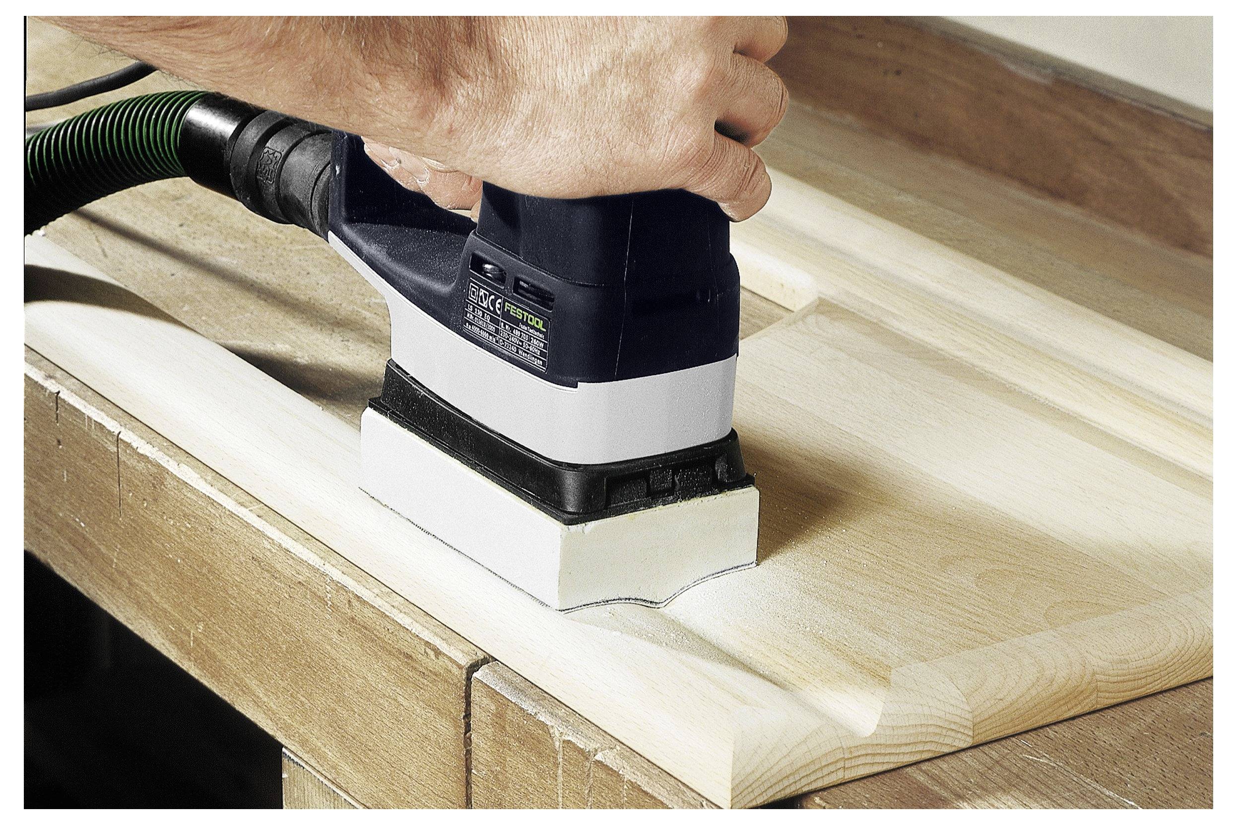 Eine Person benutzt einen elektrischen Schleiffer auf einer roten Oberfläche und glättet diese mit Präzision. Der Schleiffer trägt die Bezeichnung 