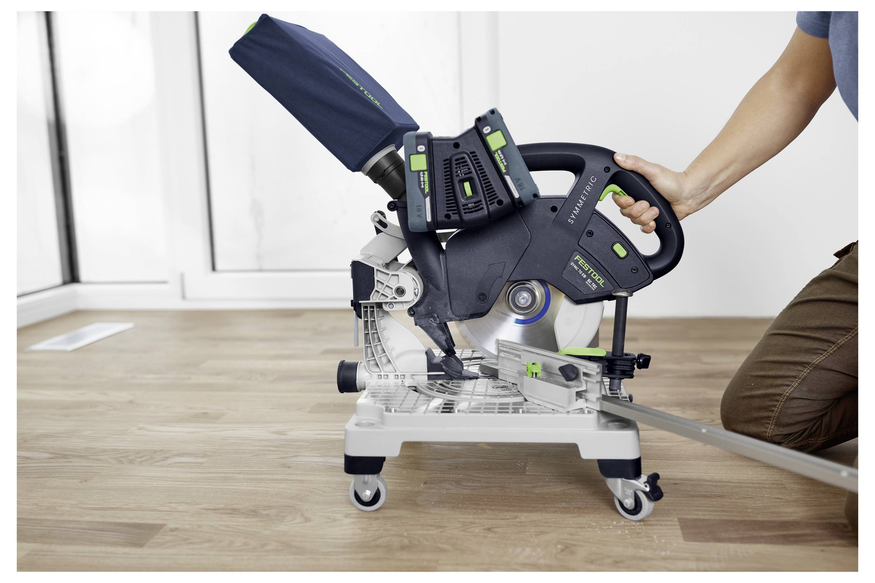 Eine Person, die die Verwendung einer Kreissäge mit Gehrungsschnitt auf einem Holzboden demonstriert, wobei der Fokus auf dem Griff und der Positionierung für Genauigkeit liegt.