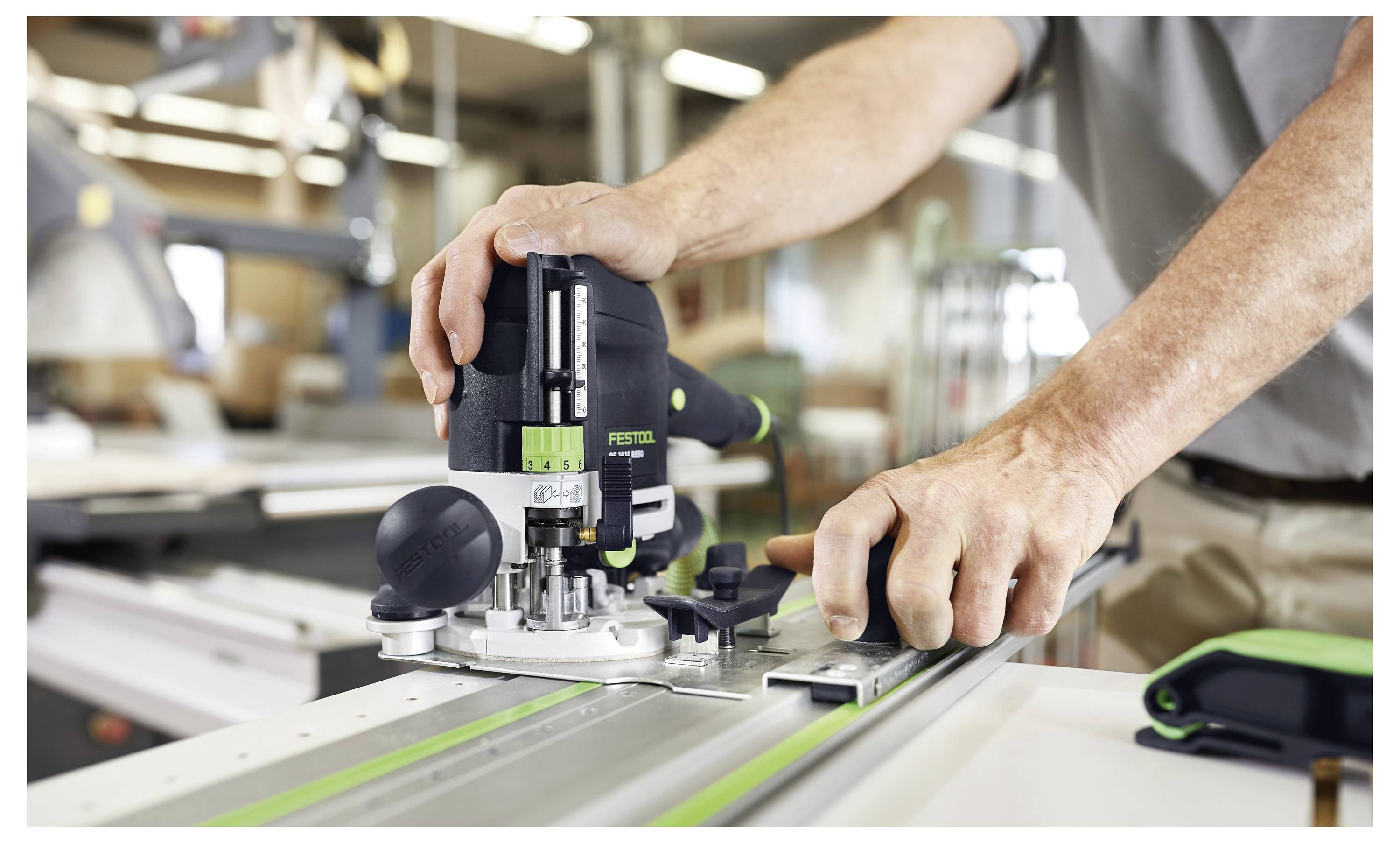 Eine Person bedient ein Oberfräsenwerkzeug auf einer Führungsschiene zum präzisen Holzzuschnitt in einer Werkstatt, wobei handwerkliches Geschick und Genauigkeit hervorgehoben werden.