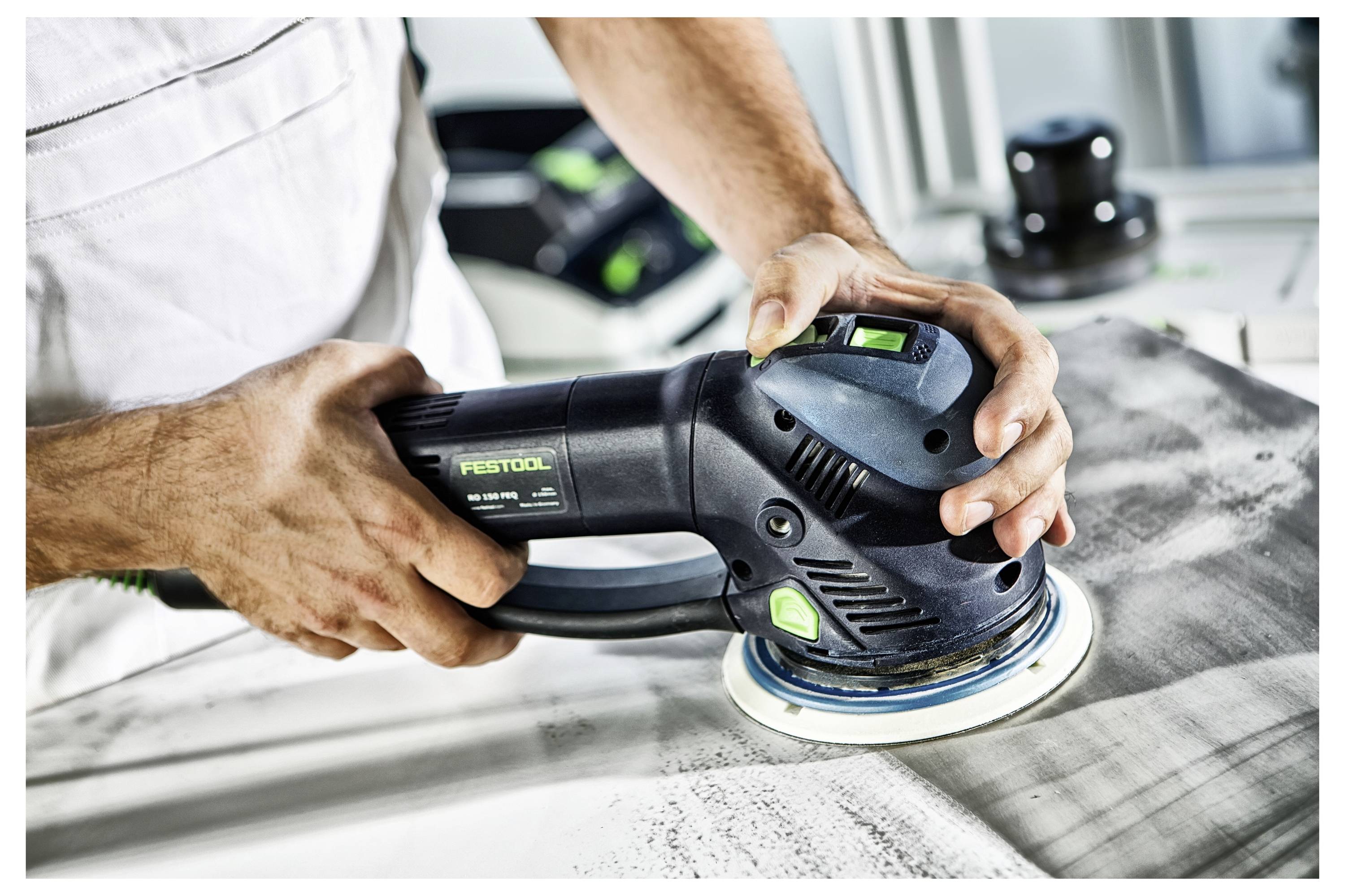 Eine Person, die einen elektrischen Schleiffer auf einer Holzoberfläche verwendet, wobei der Fokus auf dem Glätten und Fertigstellen des Materials liegt.