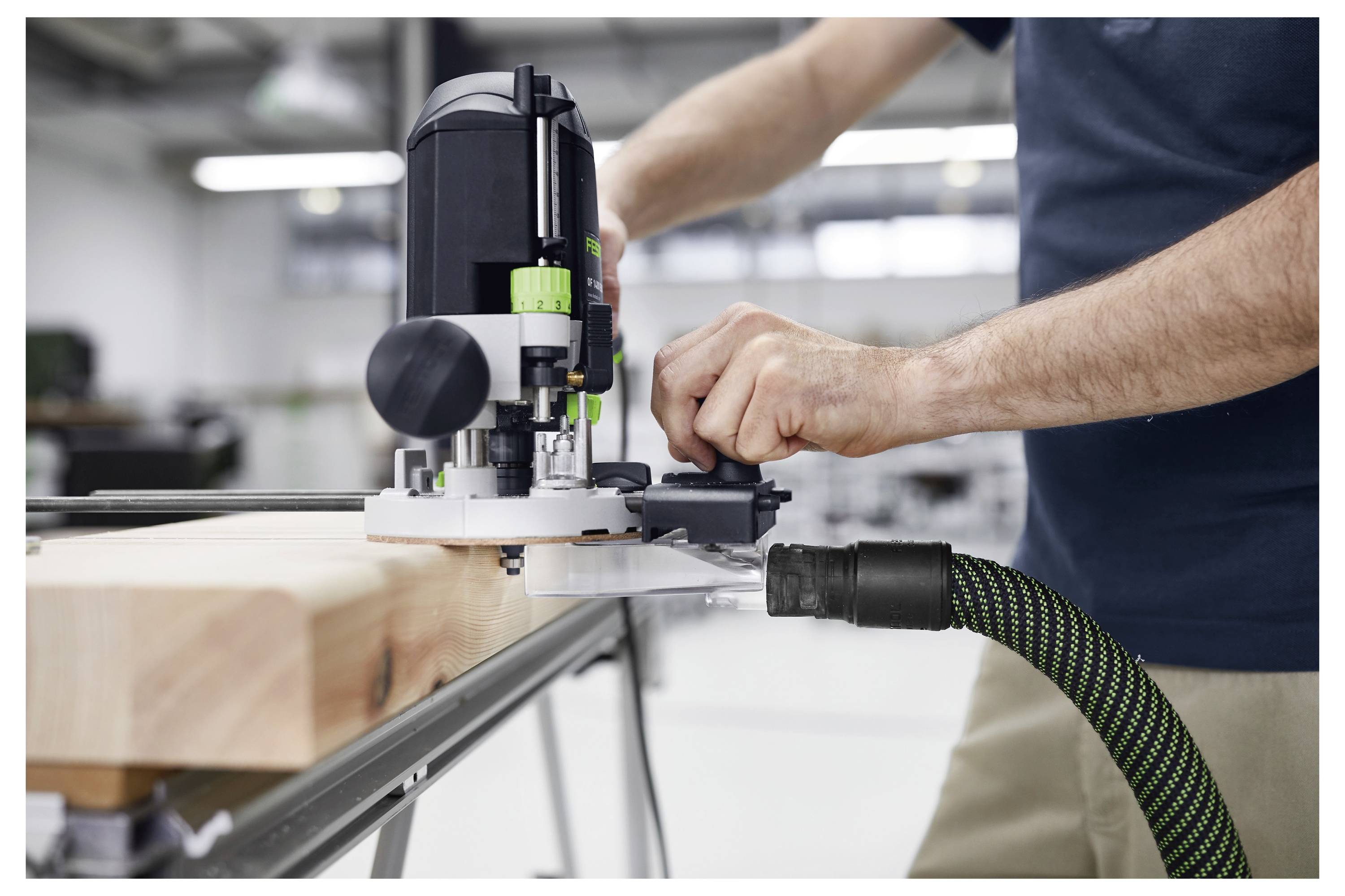 Eine Person benutzt ein Elektrowerkzeug zum Schleifen einer Holzplanke auf einer Werkbank in einer Werkstattumgebung.
