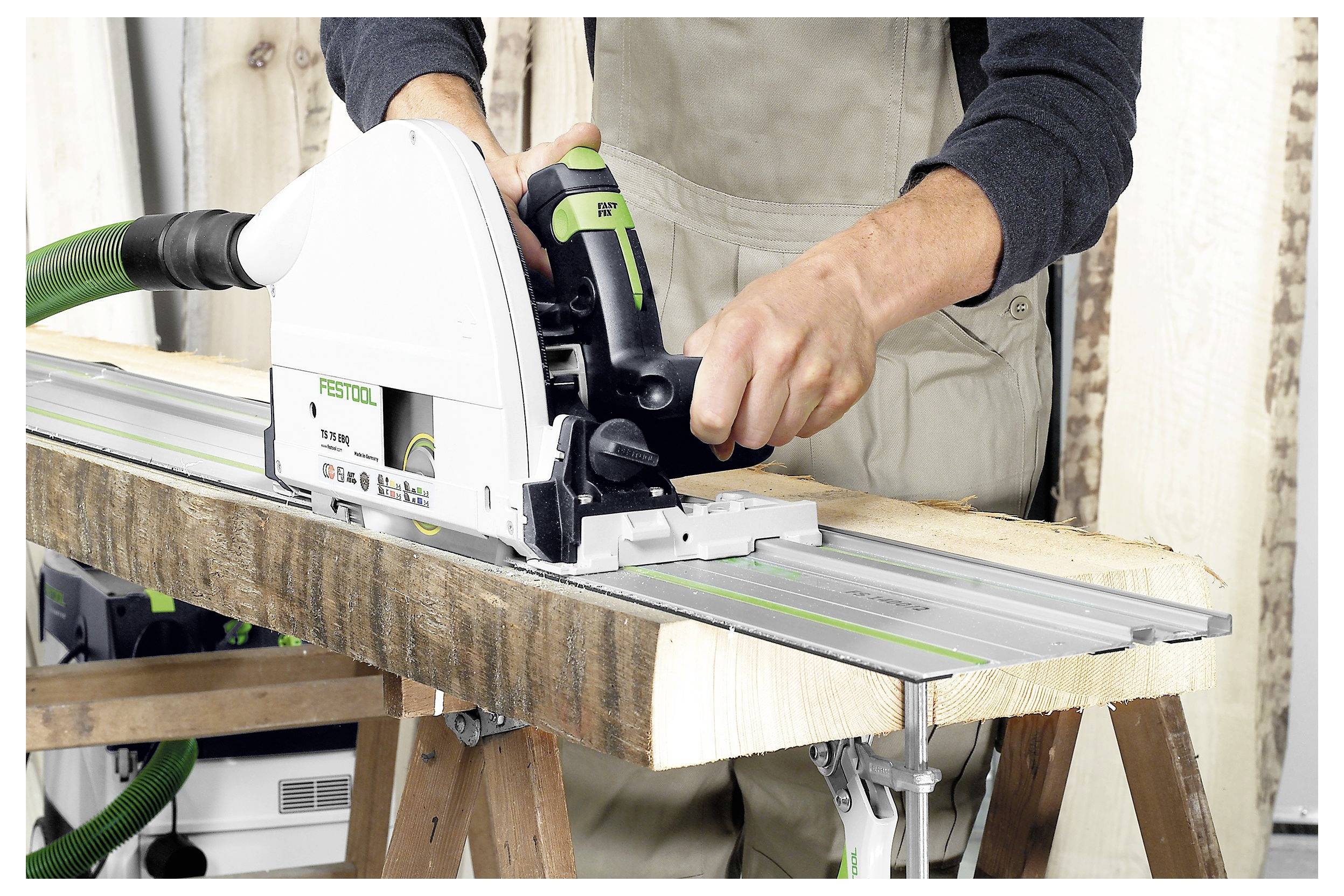 Eine Person, die eine Festool-Schienensäge verwendet, um ein Holzbrett auf Sägeböcken zu schneiden, mit präzise ausgerichteter Ausrüstung für geraden Schnitt.