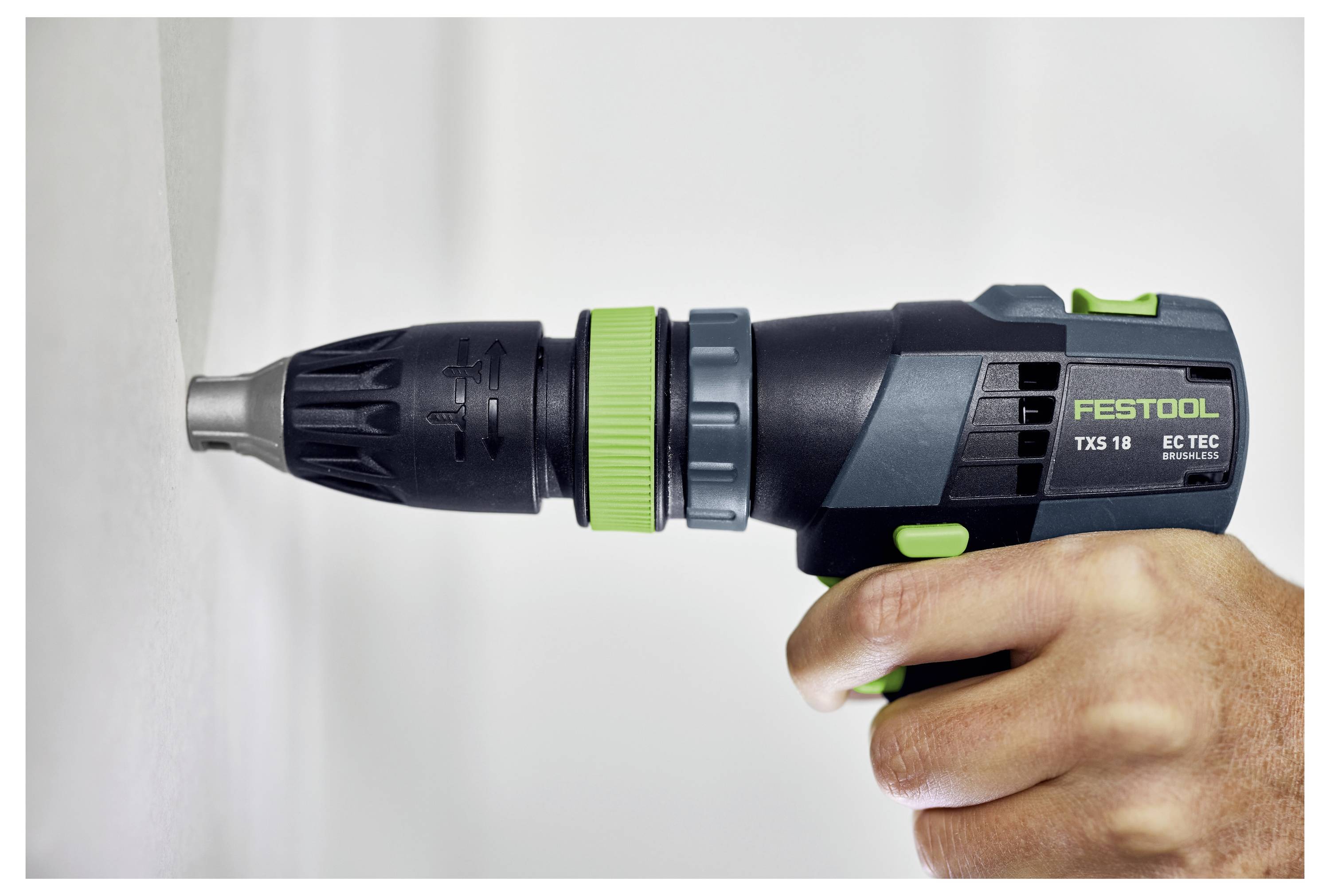Eine Person, die einen Festool TXS 18 Akku-Bohrer verwendet, um in eine weiße Oberfläche zu schrauben, während sie dessen Funktion in einem Heimwerker-Kontext demonstriert.