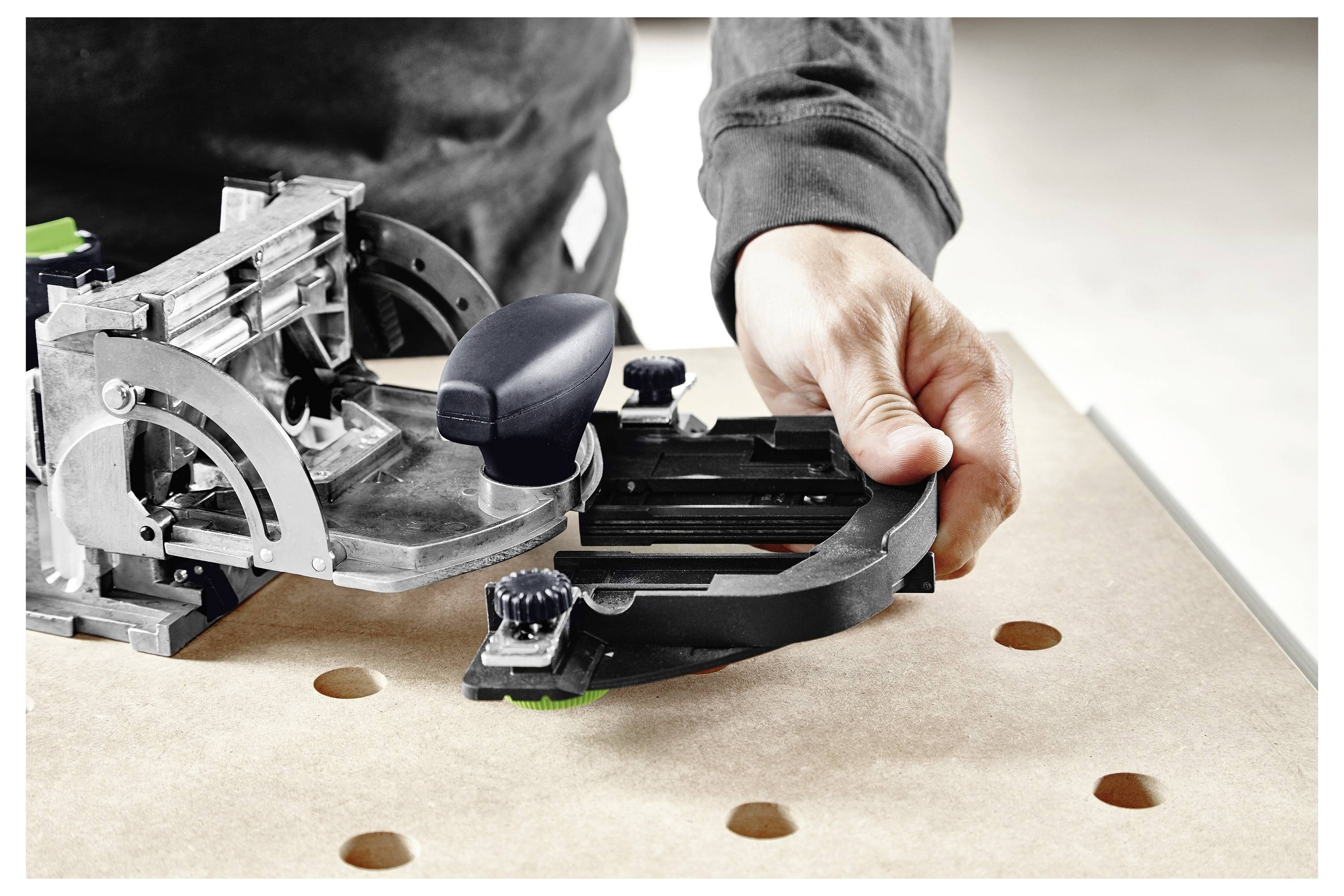 Eine Person bedient ein Holzbearbeitungswerkzeug auf einer gebohrten Holzoberfläche und stellt eine Komponente mit Präzision ein.