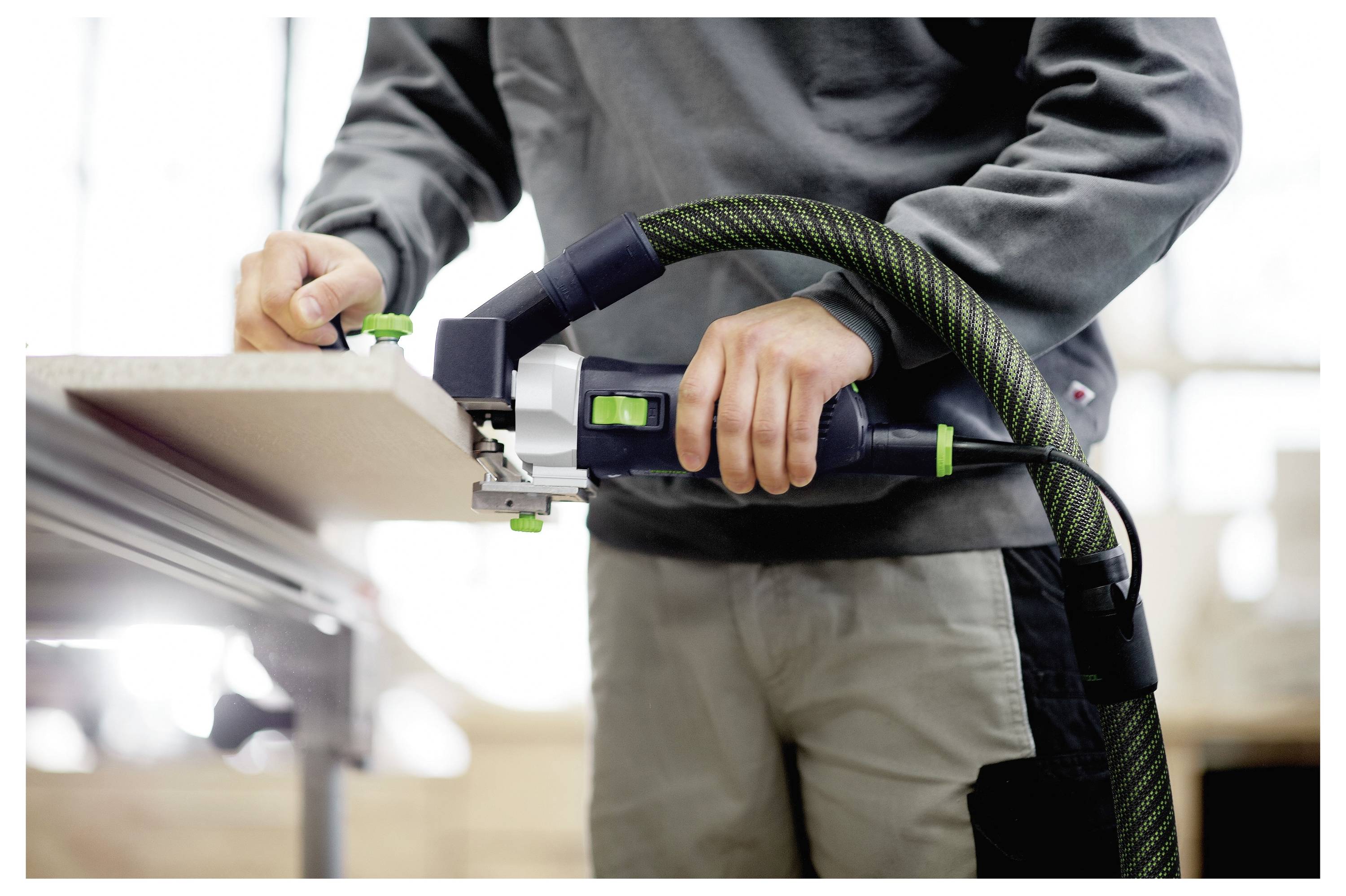 Eine Person benutzt einen Festool ETS EC 150/5 Schleifer mit einem Staubabsauger, um eine glatte Oberfläche zu schleifen, und zeigt dabei sein ergonomisches Design und seine Effizienz.