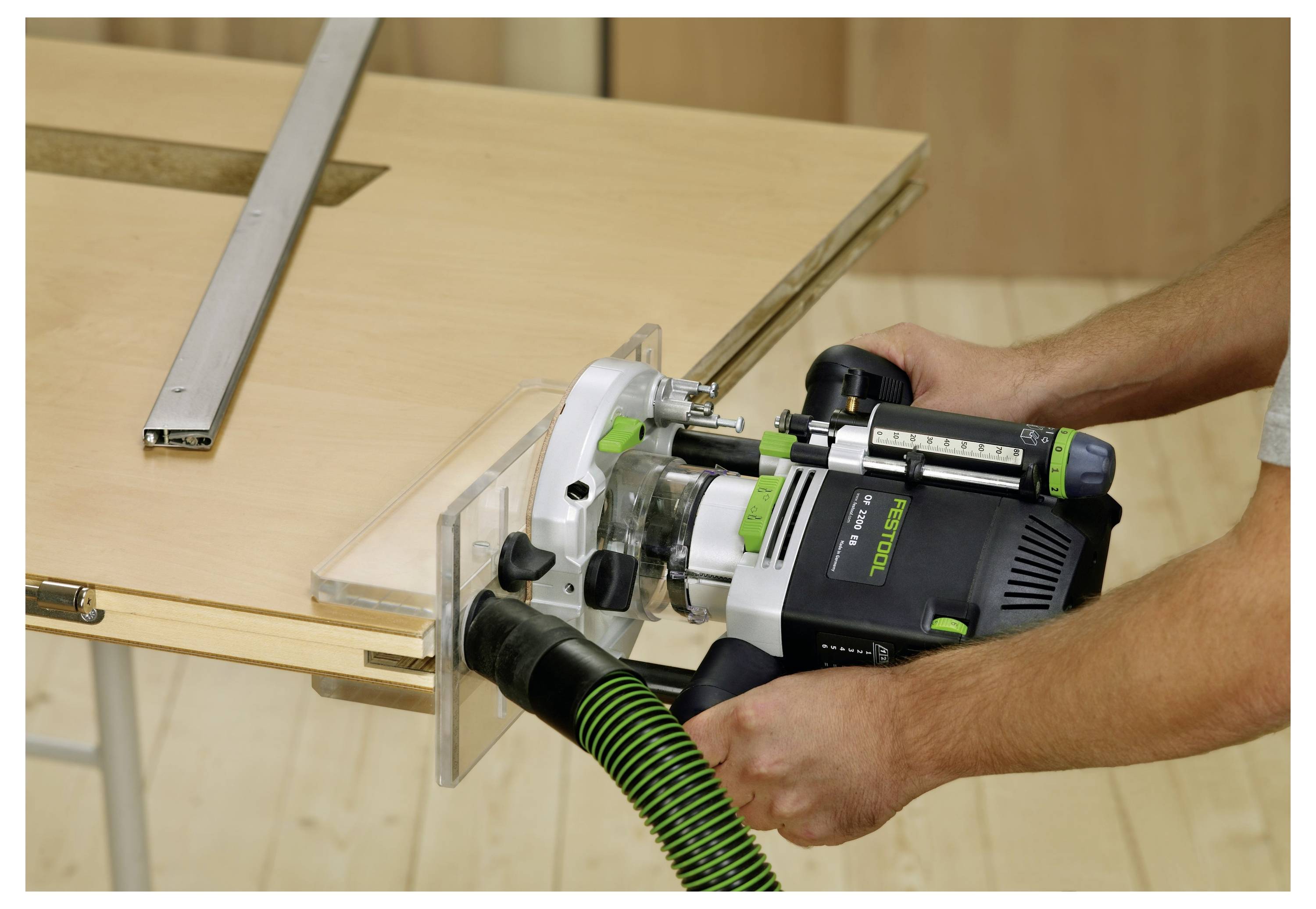 Eine Hand, die die Kante eines Holzhockers mit einem schwarzen Schleifblock abschleifen, wobei die Oberfläche geglättet wird, vor einem schlichten hellen Hintergrund.