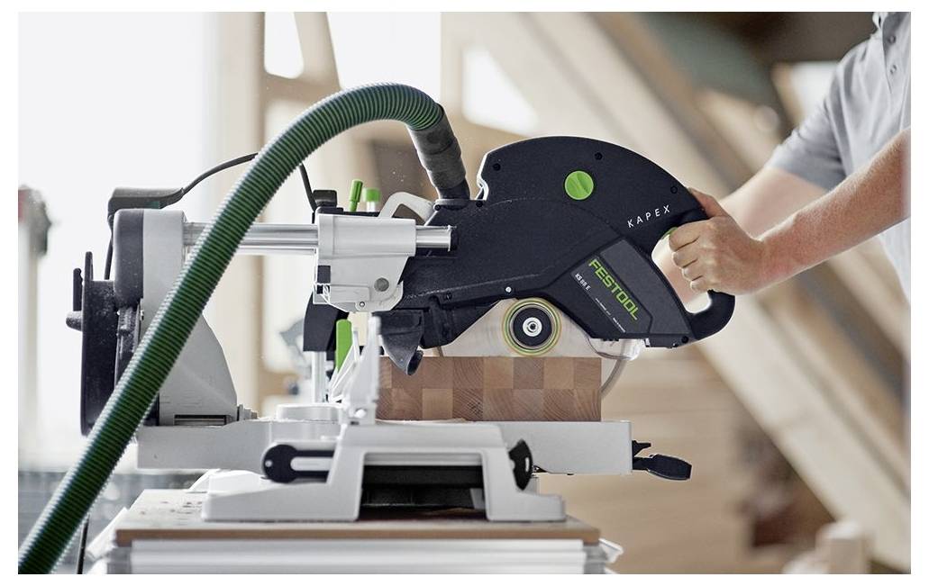 Eine Person bedient eine Präzisionssäge an einem Holzstück in einer Werkstatt und konzentriert sich darauf, einen präzisen Schnitt zu machen.