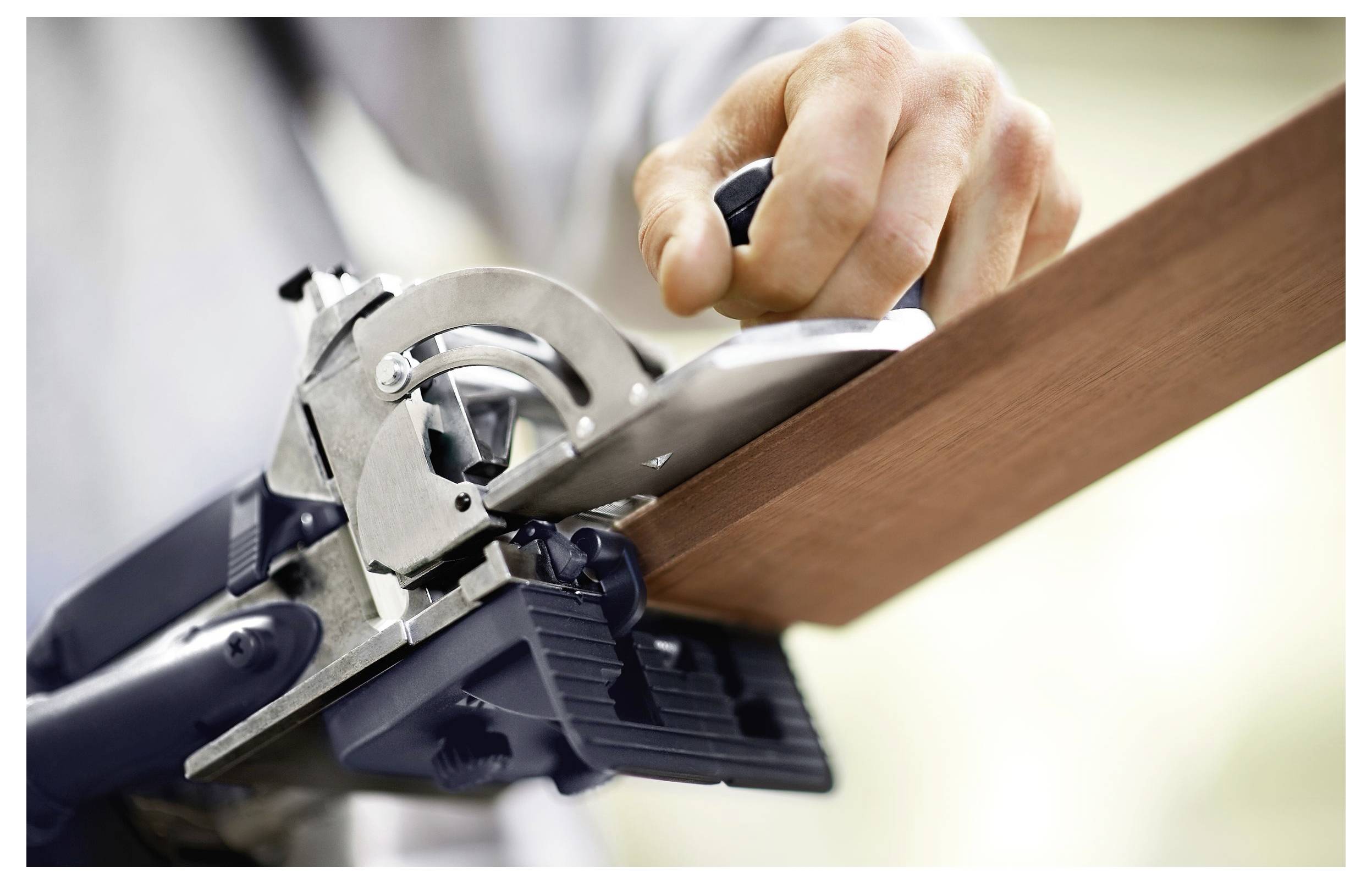 Ein unscharfes Bild, das einen Teil einer weißen, gekrümmten Oberfläche zeigt, mit einem unscharfen Objekt dahinter, möglicherweise ein Werkzeug, das eine abstrakte Szene erzeugt.