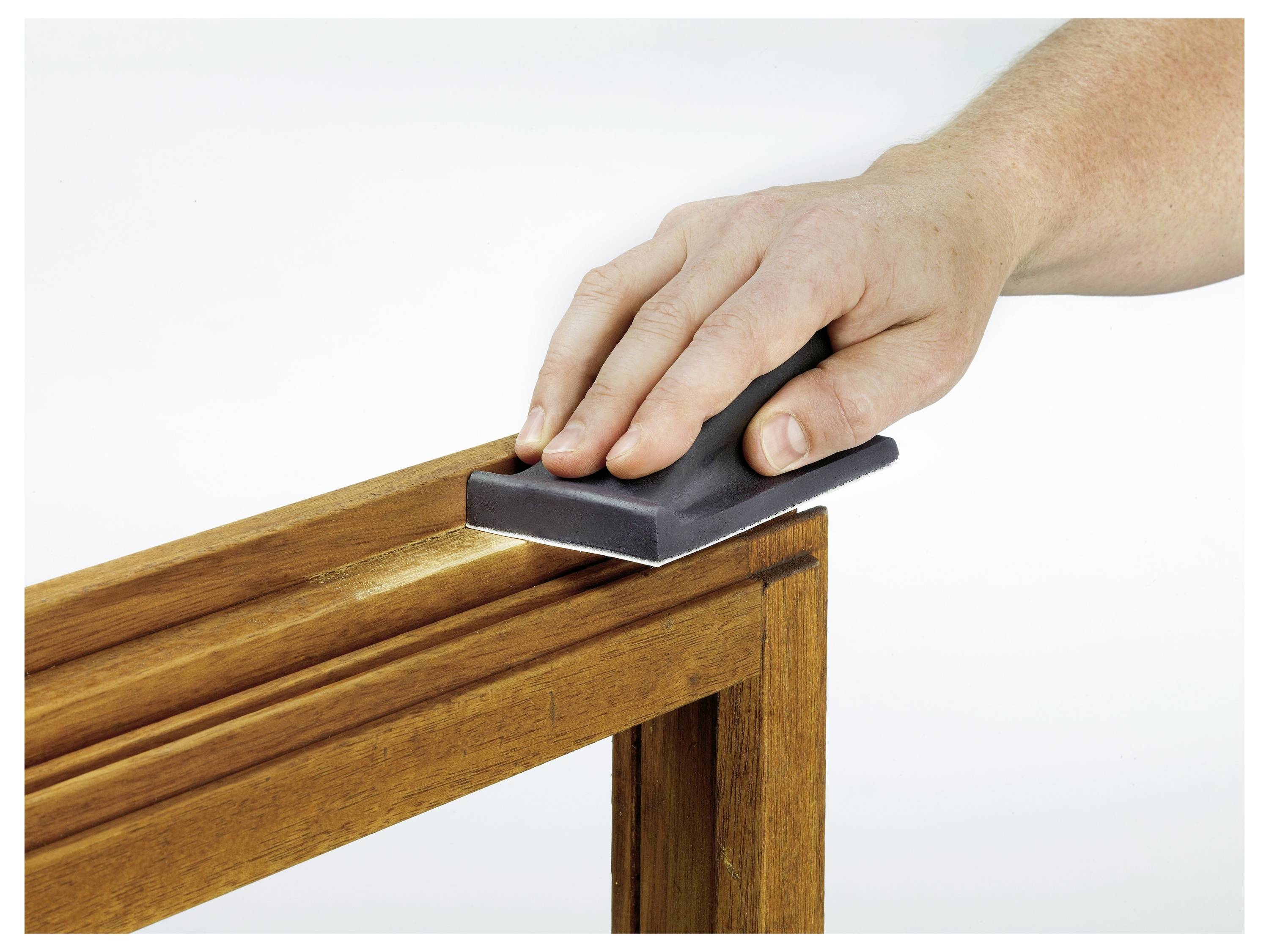 Eine Hand schleifen der Kante eines hölzernen Rahmens mit einem Schleifblock ab, was den Prozess des Glättens von Holzoberflächen demonstriert.