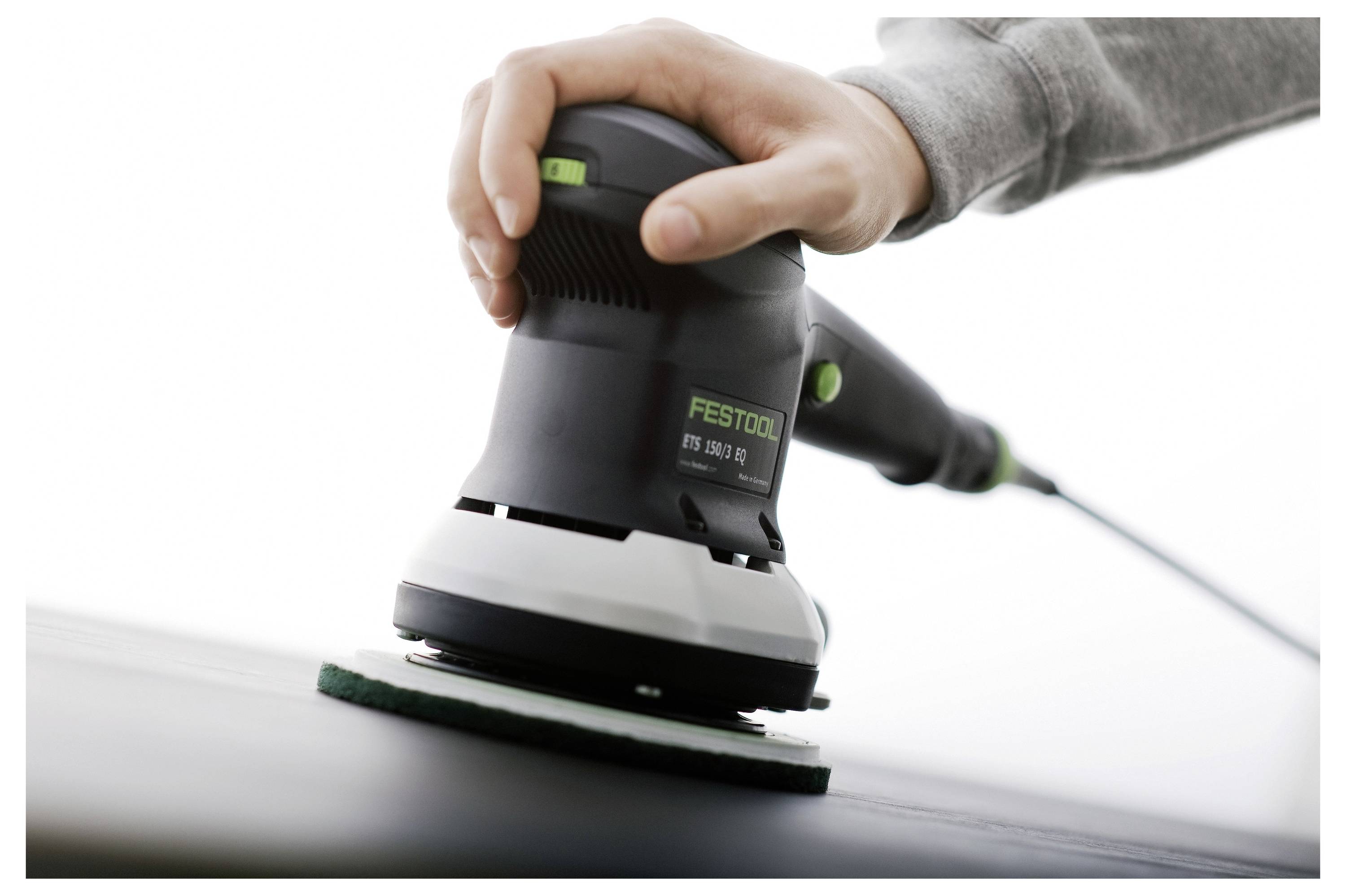 Eine Hand bedient einen Festool Elektroschleiffer auf einer ebenen Fläche und zeigt dabei die sanfte Schleifbewegung und die Designmerkmale des Werkzeugs.