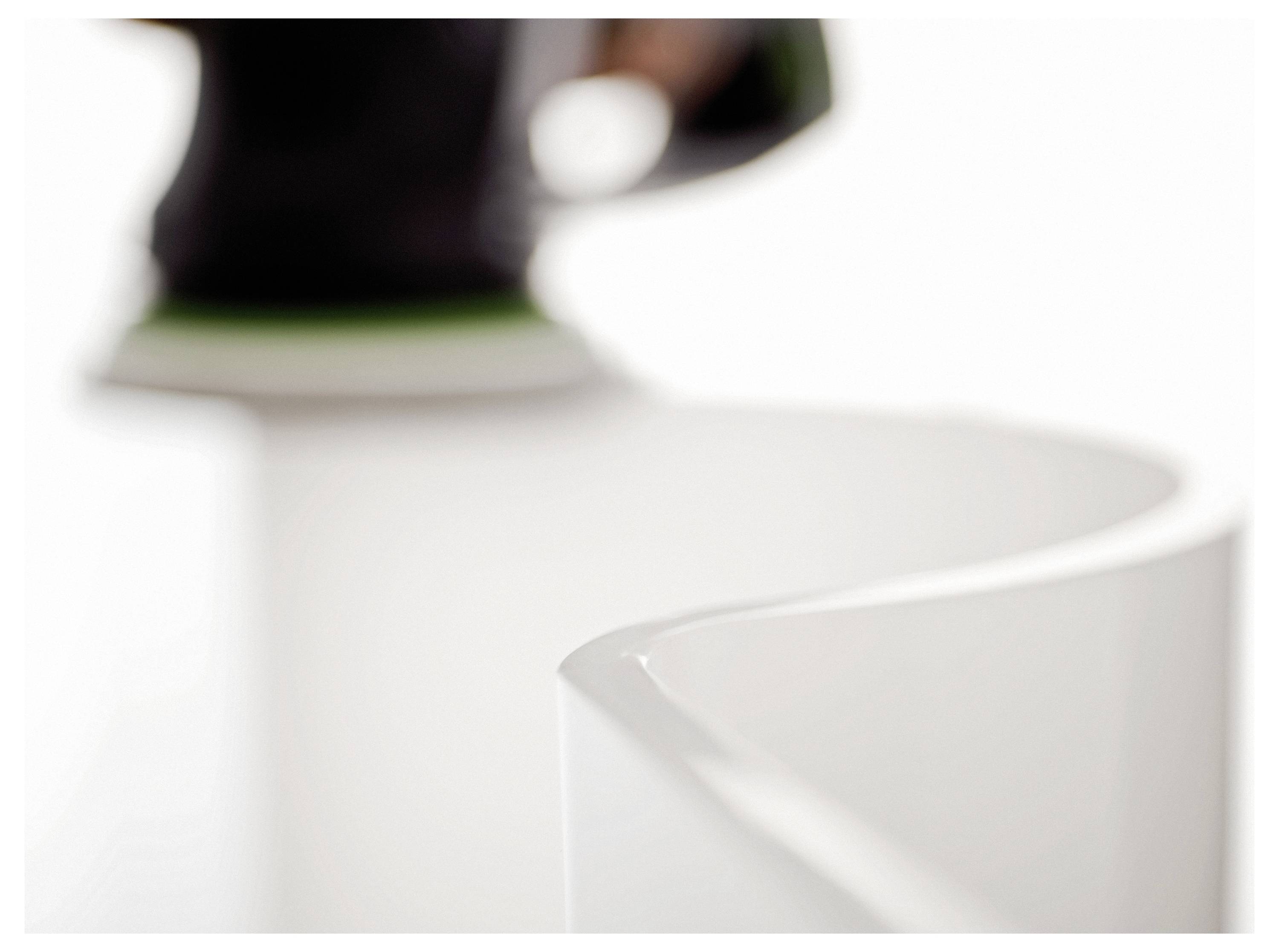 Eine unscharfe Nahaufnahme einer Kurve eines weißen Objekts, teilweise vor einem hellen Hintergrund sichtbar, die Aufmerksamkeit auf sanfte Konturen legt.