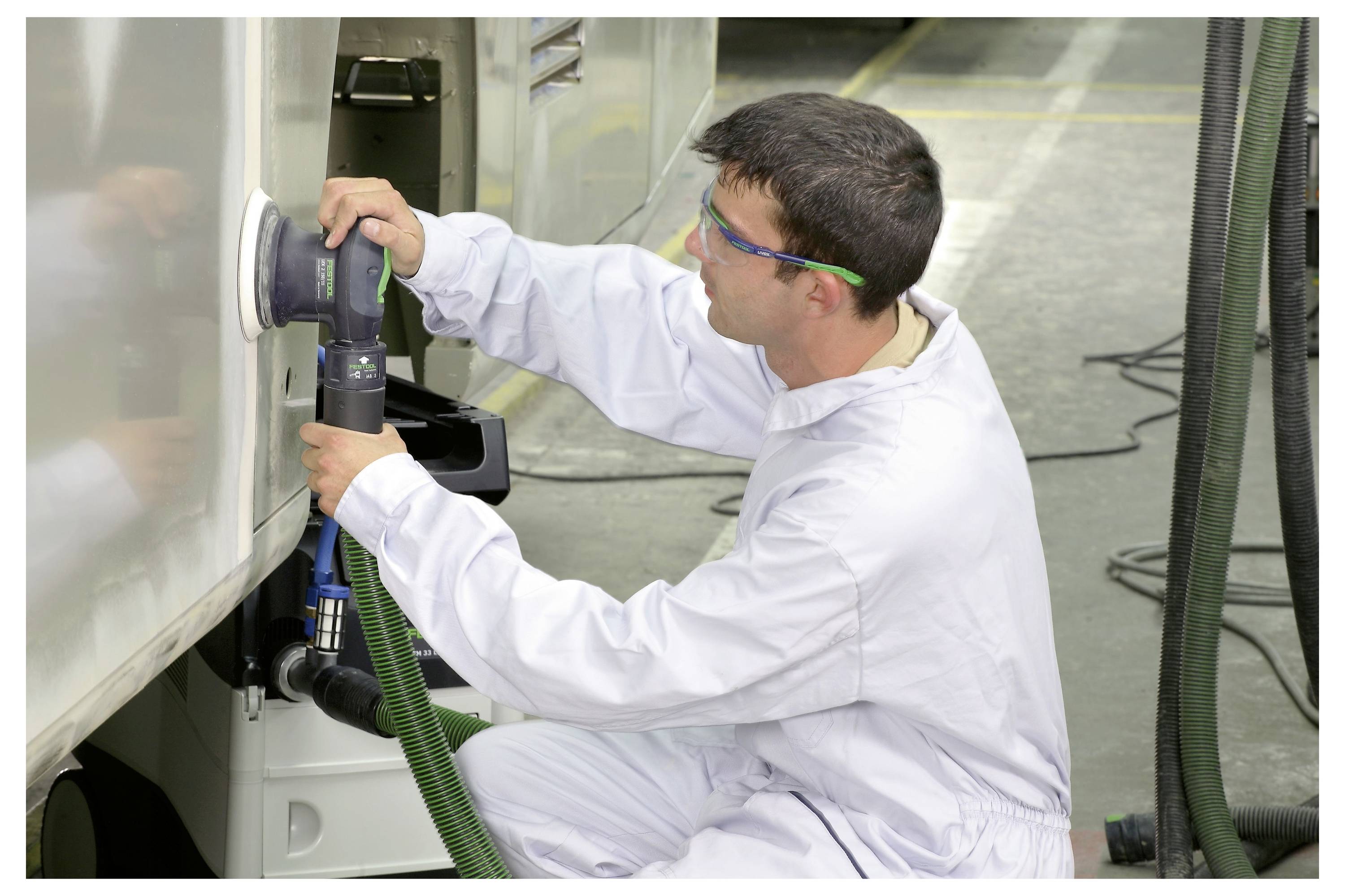 Person, die einen elektischen Schleiffer auf einer Holzoberfläche benutzt, wobei der Fokus auf der Bewegung und dem Winkel des Werkzeugs zum Glätten der Fläche liegt.