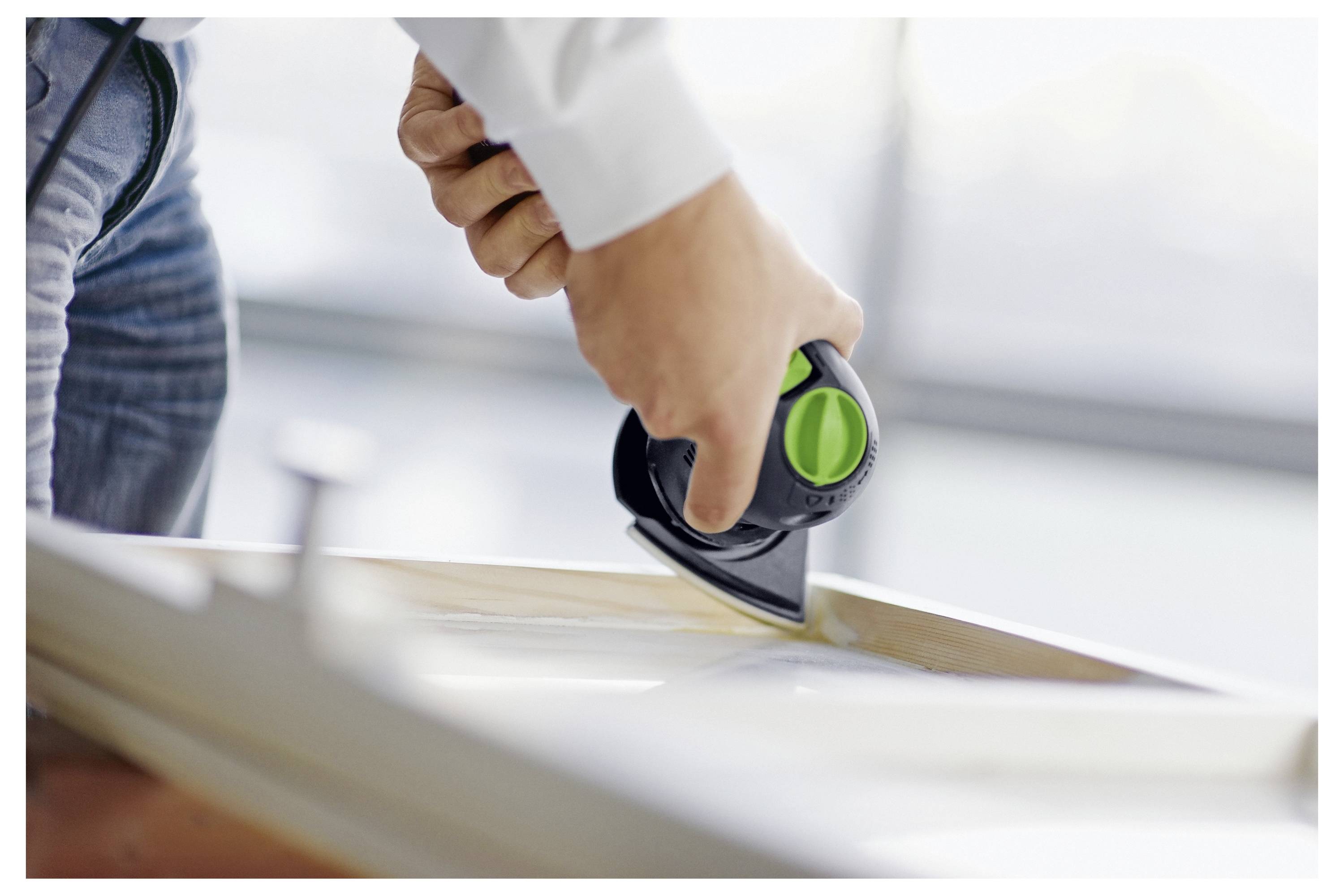 Eine Person, die ein tragbares Elektrowerkzeug verwendet, um die Kante einer Holzoberfläche zu polieren, wobei der Fokus auf präzise und detaillierte Arbeit liegt.