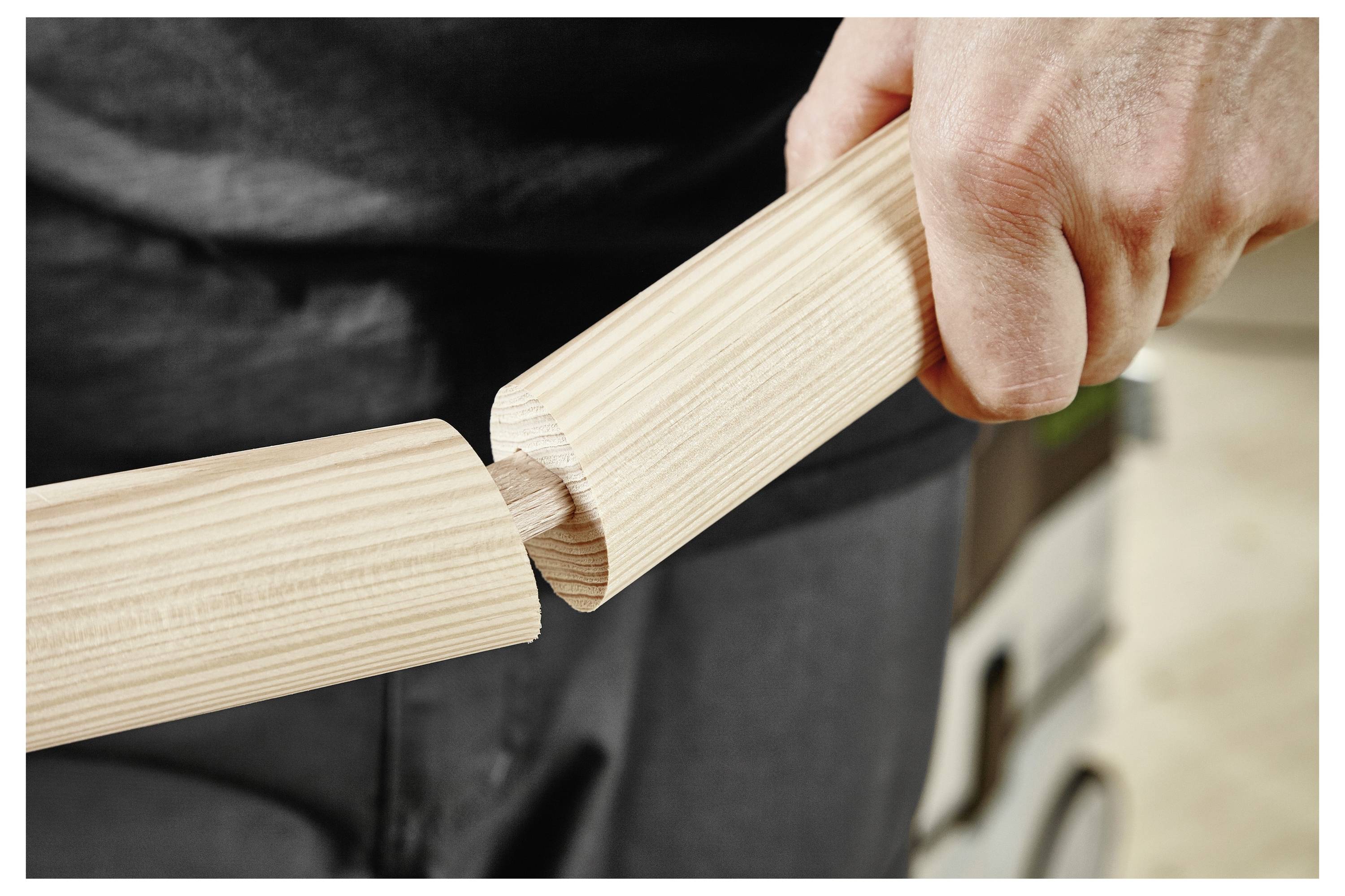 Eine Person, die Holzblöcke in eine Nut auf einem gekrümmten Holzteil auf einer Werkbank einpasst, was Holzbearbeitung oder Montage veranschaulicht.