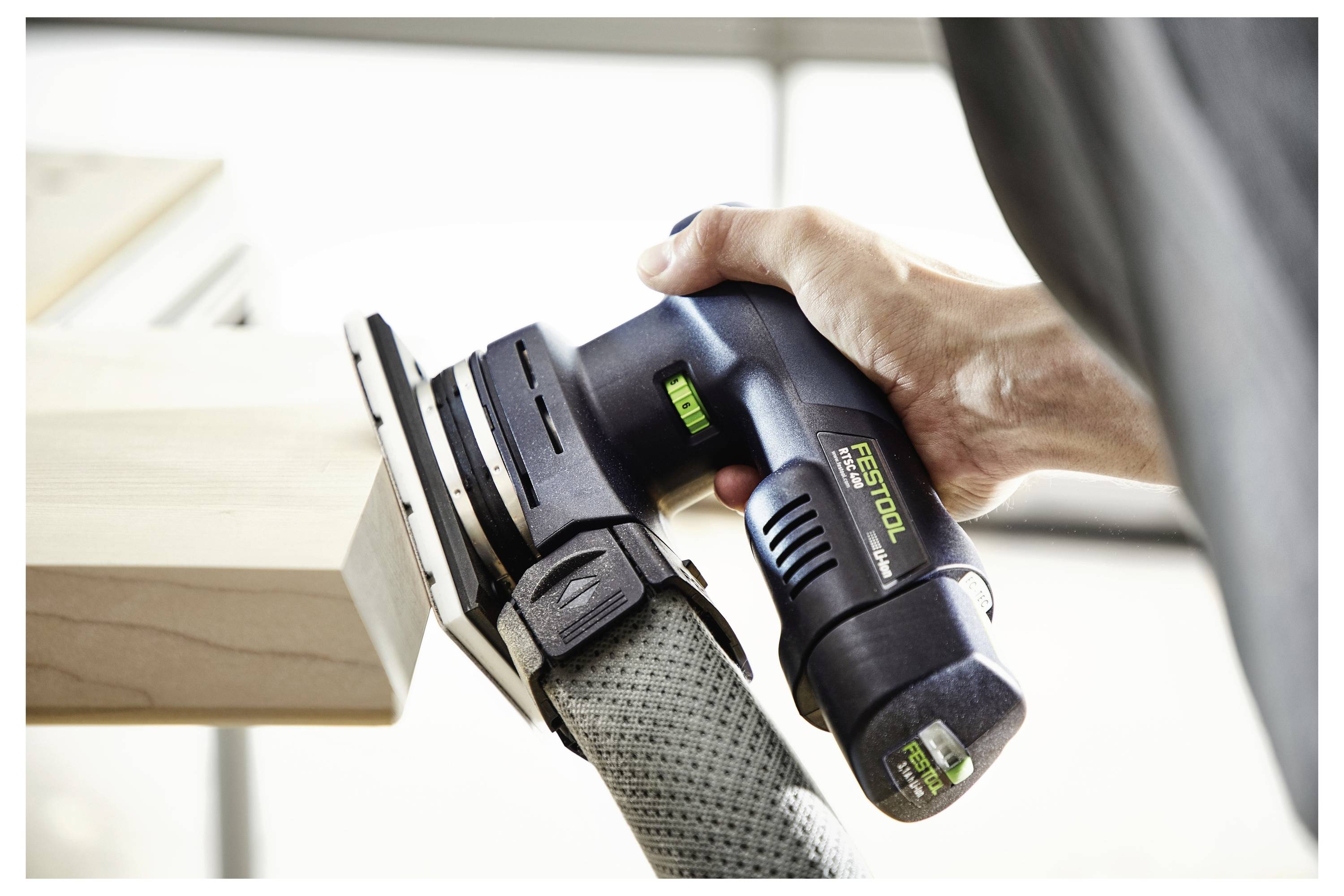 Eine Person benutzt einen Festool-Elektroschleiffer auf einer Holzoberfläche und demonstriert damit die Anwendung des Werkzeugs für glatte und polierte Oberflächenfinishes.