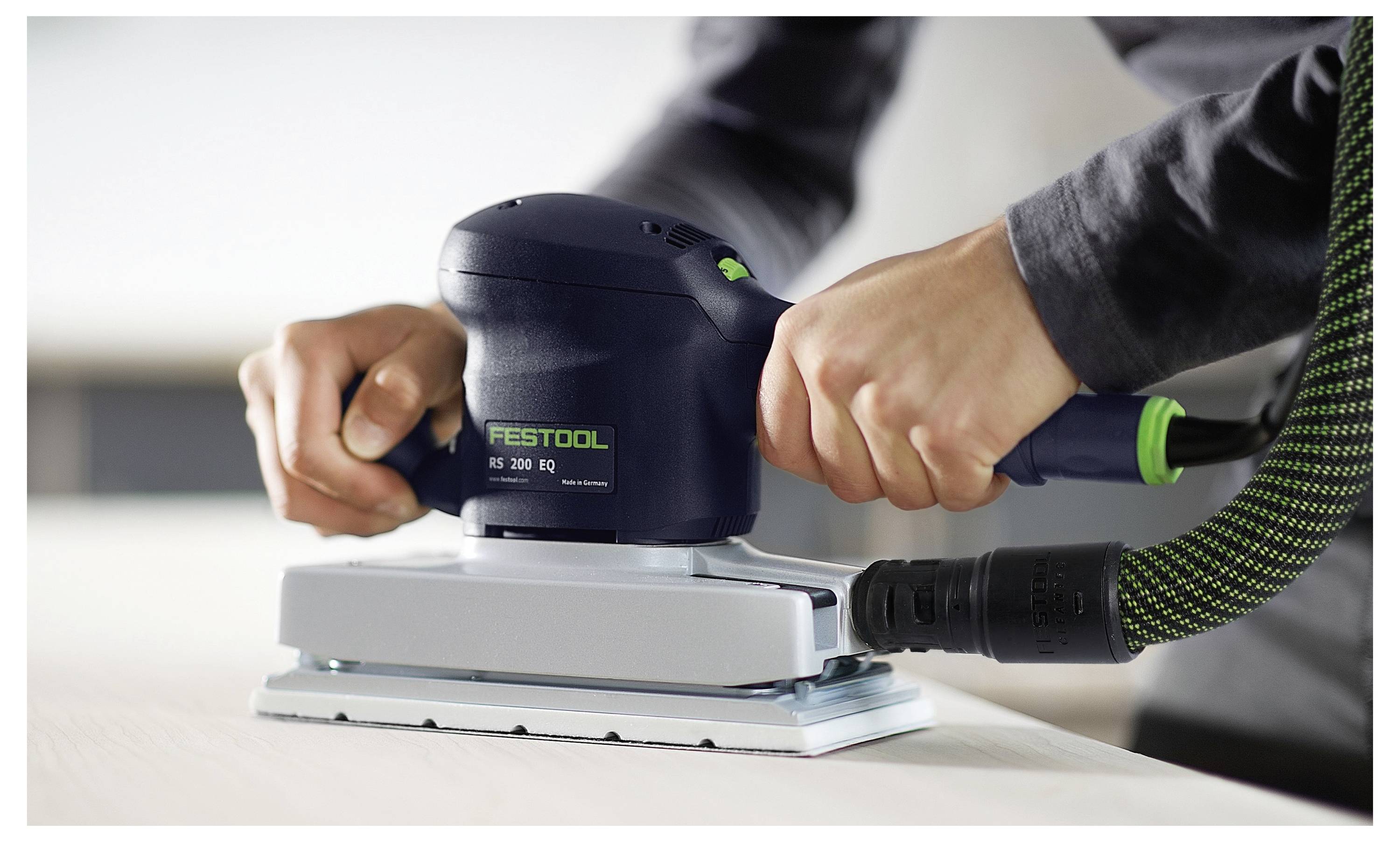 Hände, die einen Festool Elektroschleiffer auf einer Holzoberfläche verwenden, verbunden mit einem Absaugschlauch, demonstrieren das Schleifen in Arbeit.
