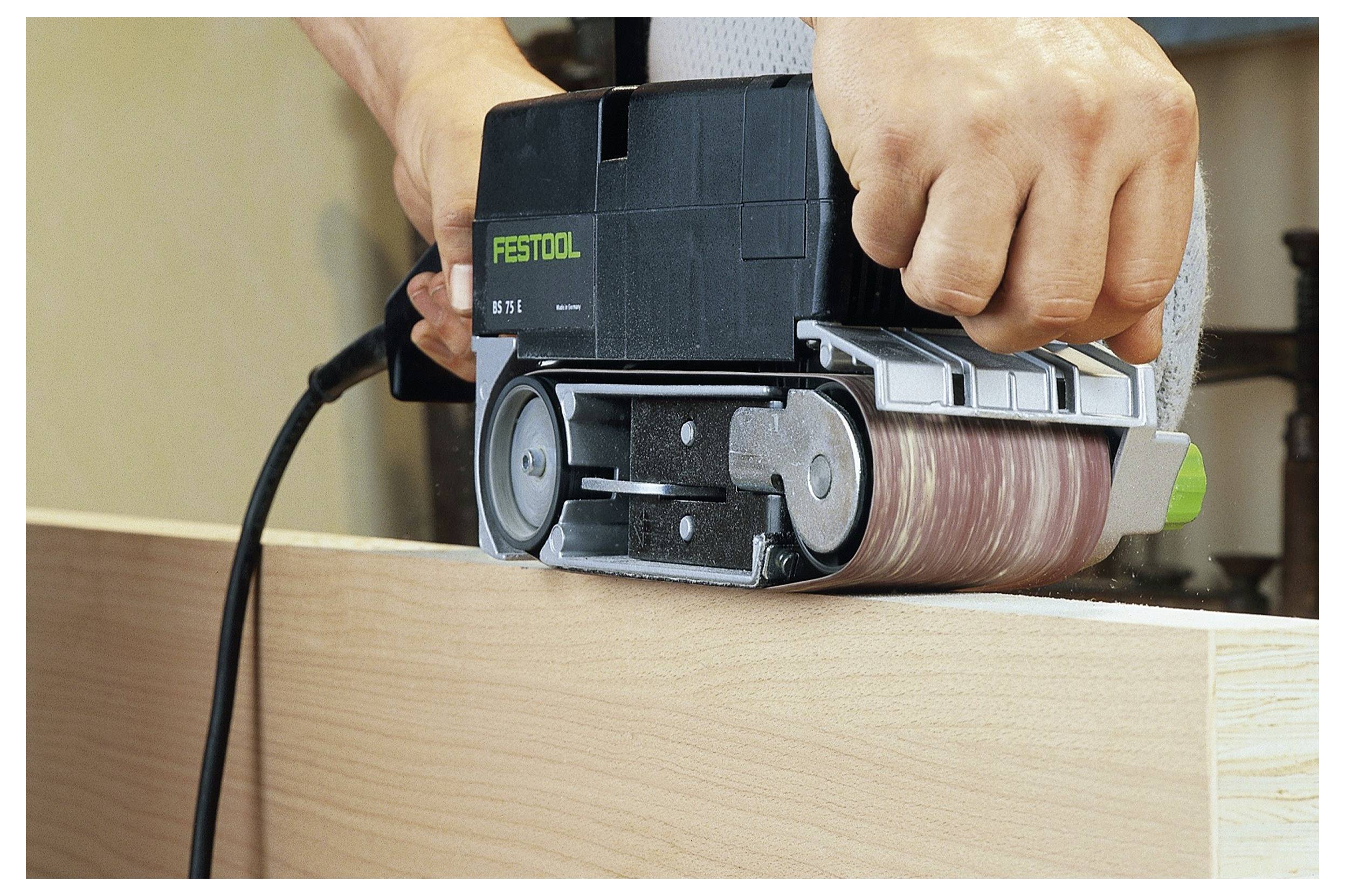 Eine Person nutzt einen Elektroschleiffer auf einer Holzoberfläche und glättet die Kante. Der Schleifer trägt die Bezeichnung „FESTOOL BS 75 E