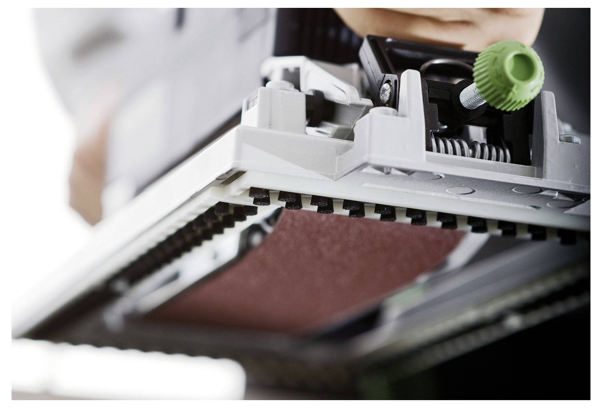 Eine Großaufnahme einer in Betrieb befindlichen Schleifmaschine, die das Schleifpad und den Einstellknopf zeigt. Das Bild konzentriert sich auf Mechanik und Präzision.