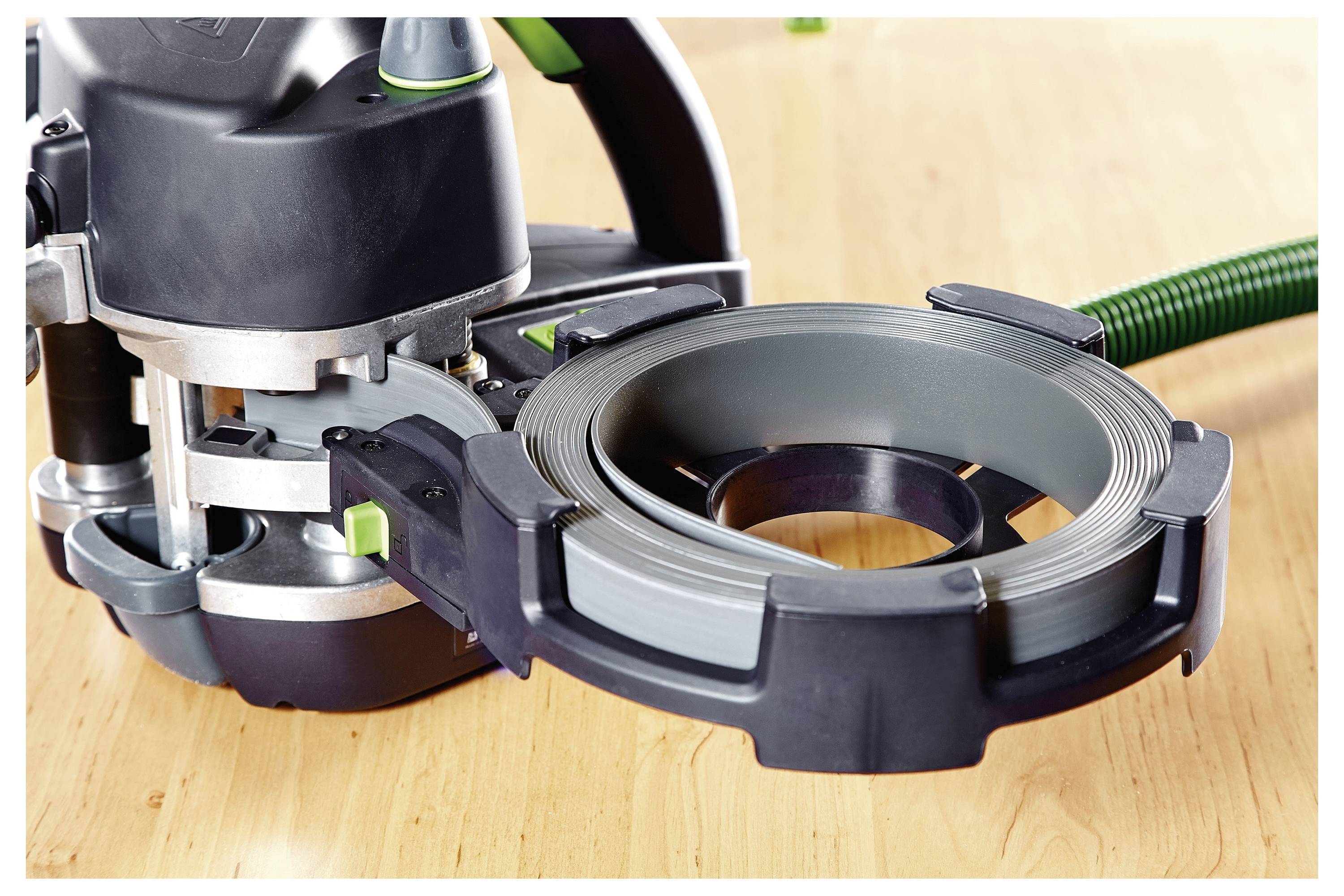 Ein schwarz-grünes Kantenumleimer-Werkzeug auf einer Holzoberfläche, das zum Aufbringen von Kantenbändern auf Möbelkanten verwendet wird.