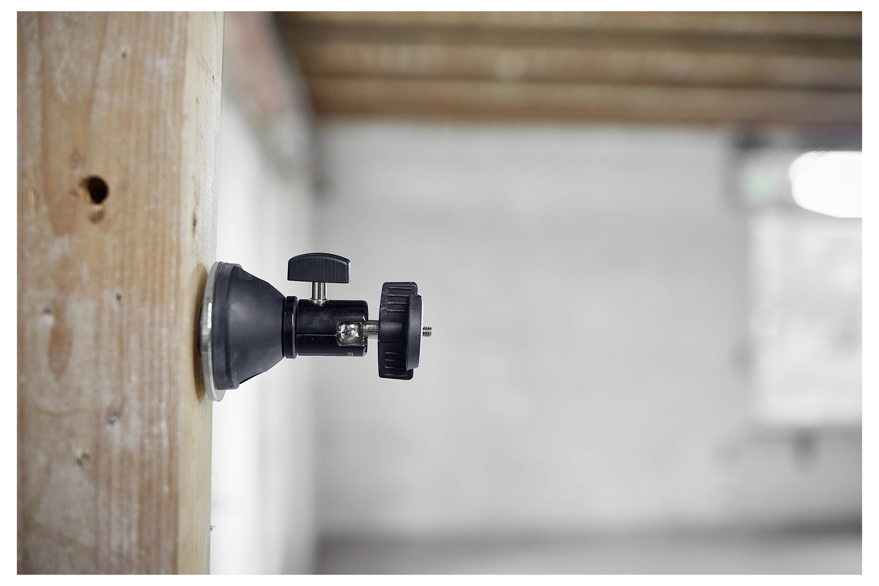 Seitenansicht einer Kamerahalterung, die an einer Holzoberfläche in einem unfertigen Raum befestigt ist, mit unscharfem Hintergrund von Wänden und Decke.