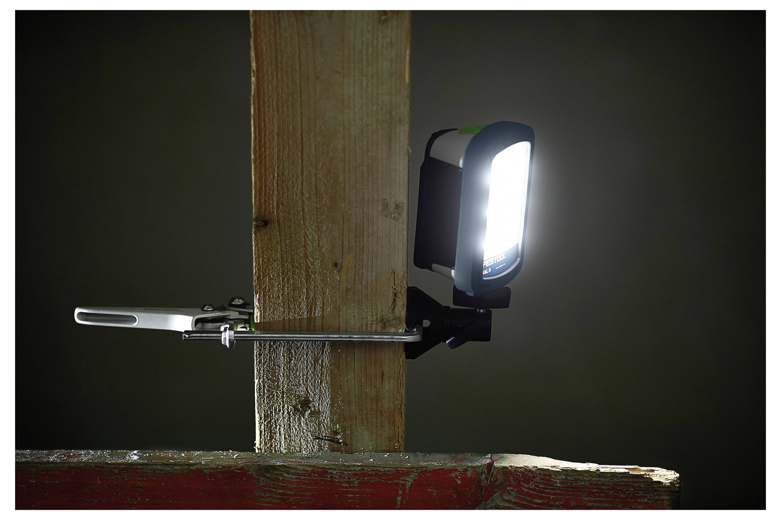 Eine helle Arbeitsleuchte ist sicher an einem vertikalen Holzbalken befestigt und erleuchtet einen schwach beleuchteten Raum.