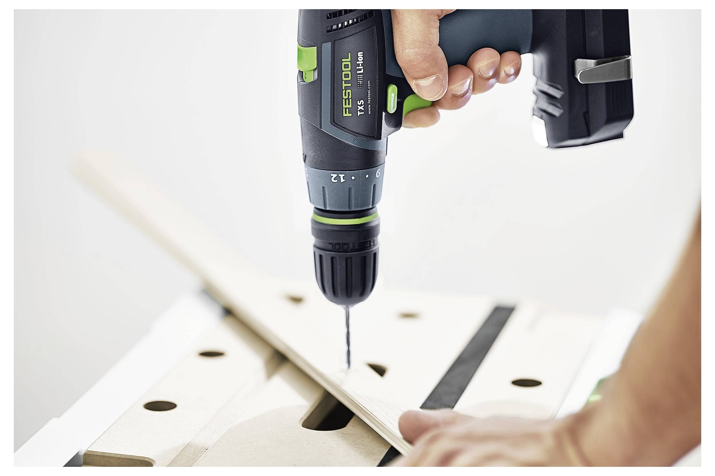 Eine Person verwendet einen kabellosen Bohrer, um ein Loch in ein Stück Holz auf einer Werkbank zu bohren, was die Anwendung des Werkzeugs in der Holzbearbeitung zeigt.