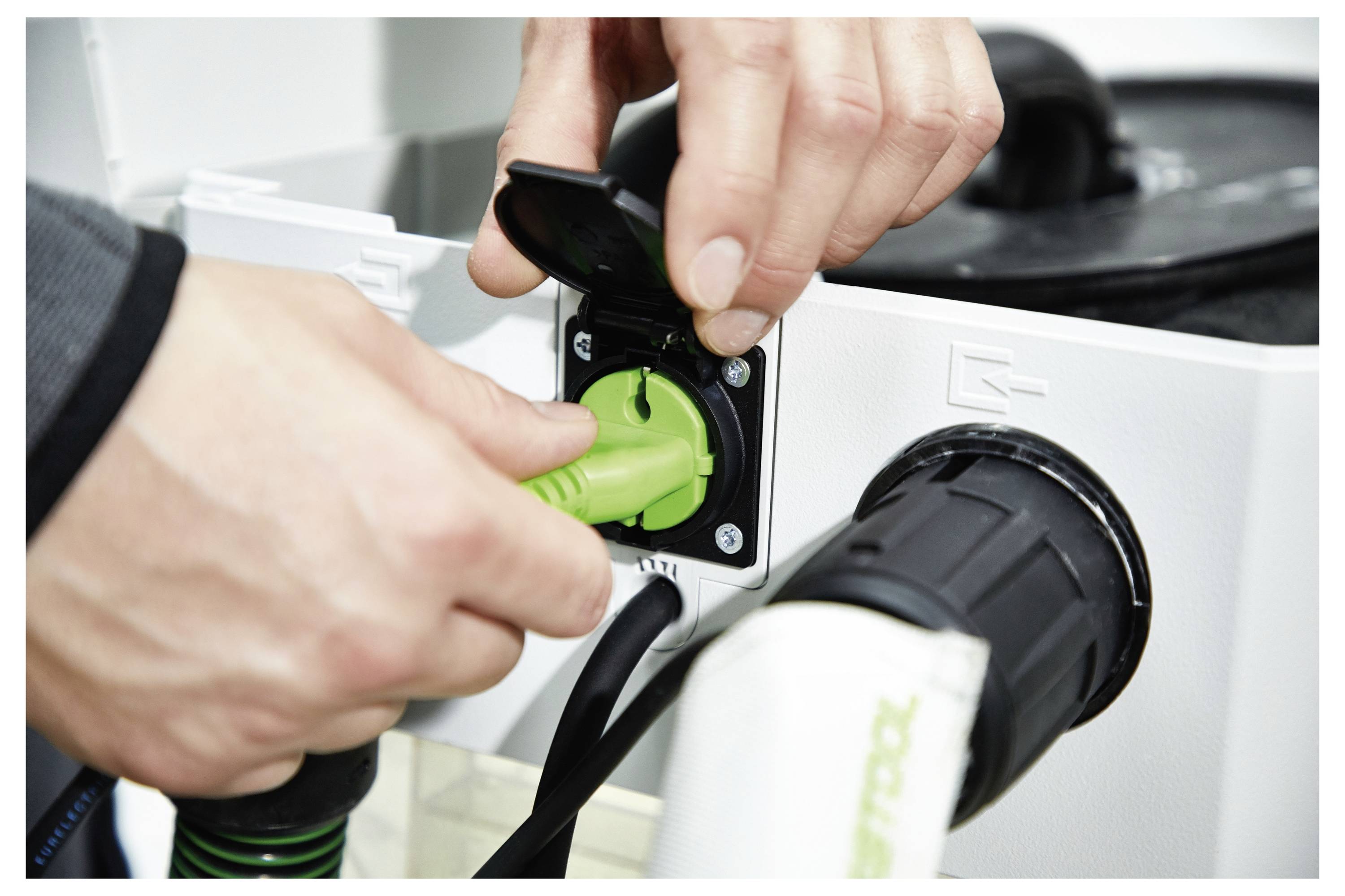 Person, die einen Deckenwinkelschleifer in einem teilweise fertigen Raum benutzt, mit offenen Deckenpaneelen und einem großen Fenster im Hintergrund.