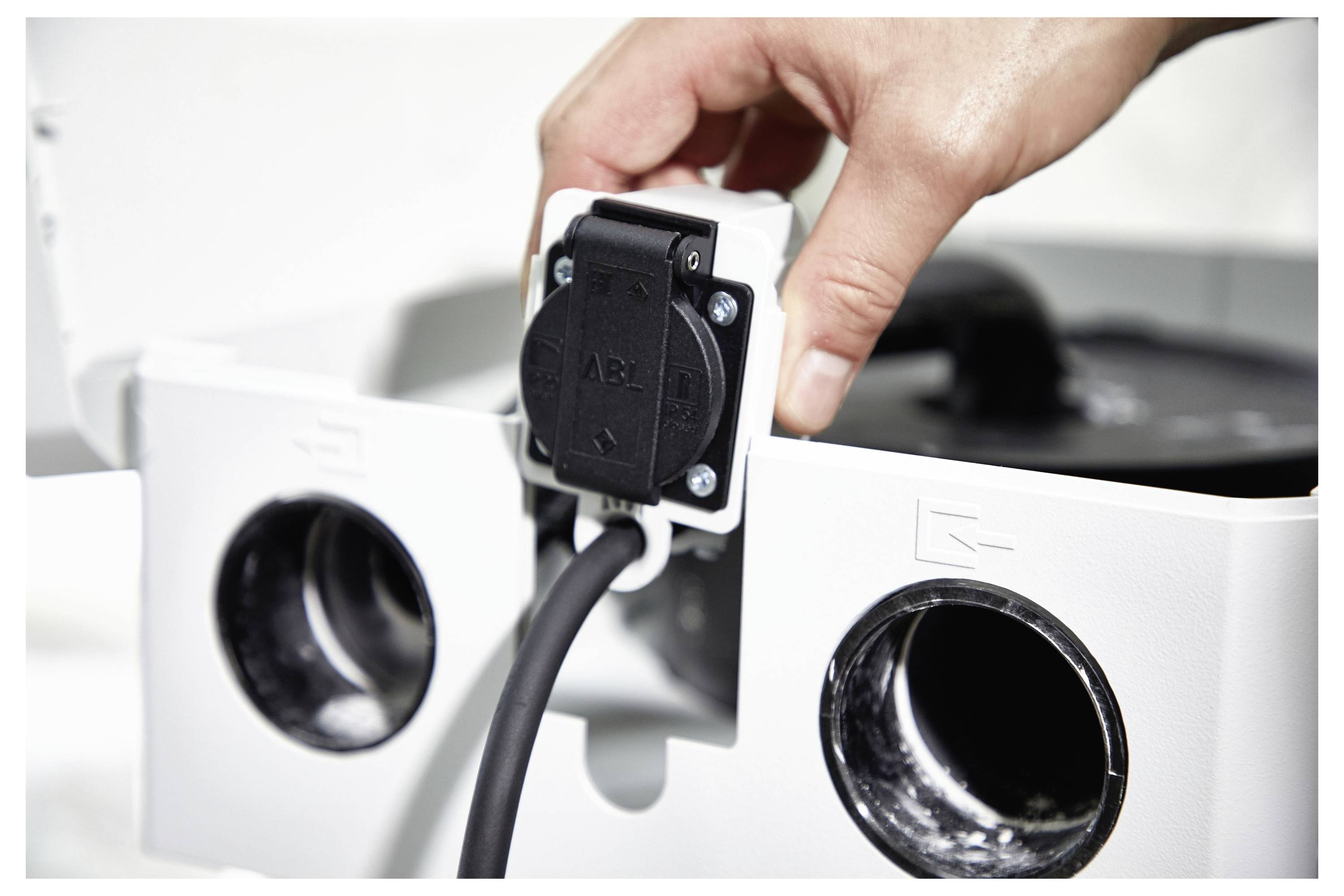 Person in einem grauen Hemd, die einen kabellosen Bohrer in einer Werkstatt verwendet.