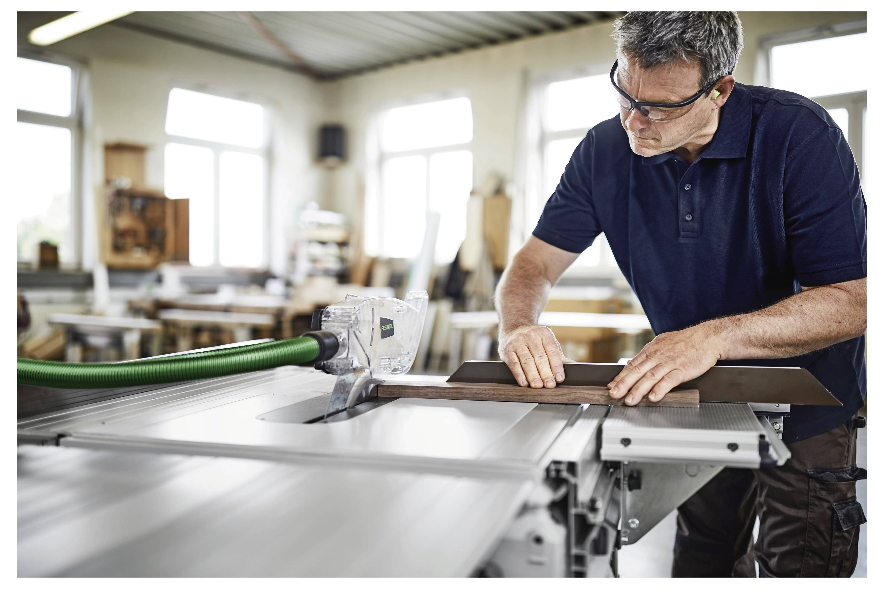 Ein Mann mit Schutzbrille und Handschuhen benutzt eine Elektrobohrmaschine an einer Betonwand und betont damit sichere Praktiken im Baugewerbe.