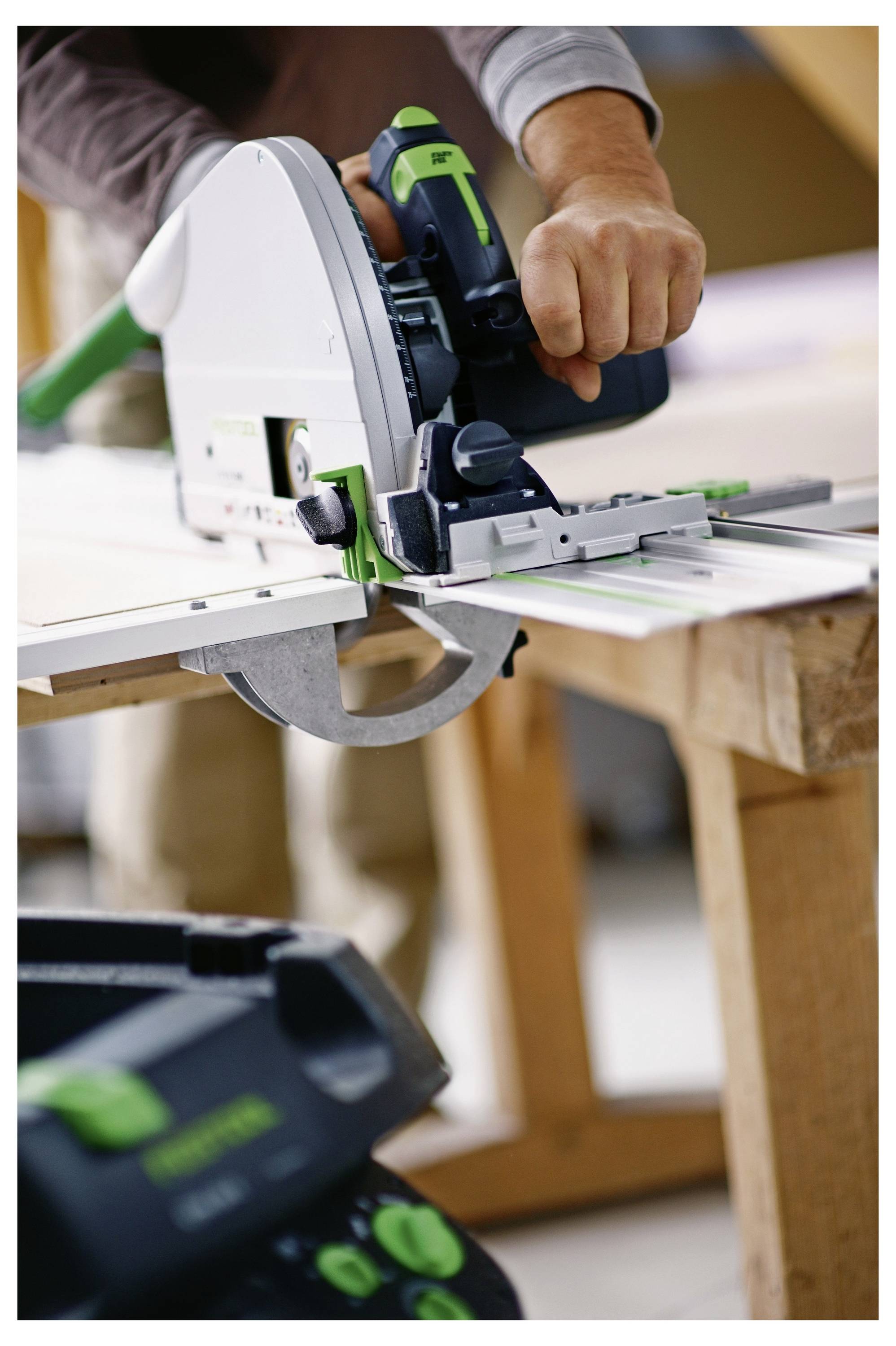 Eine Hand, die einen Schraubendreher verwendet, um ein Scharnier an einem Möbelstück einzustellen, deutet auf Montage- oder Reparaturarbeiten in einem hellen Arbeitsbereich hin.