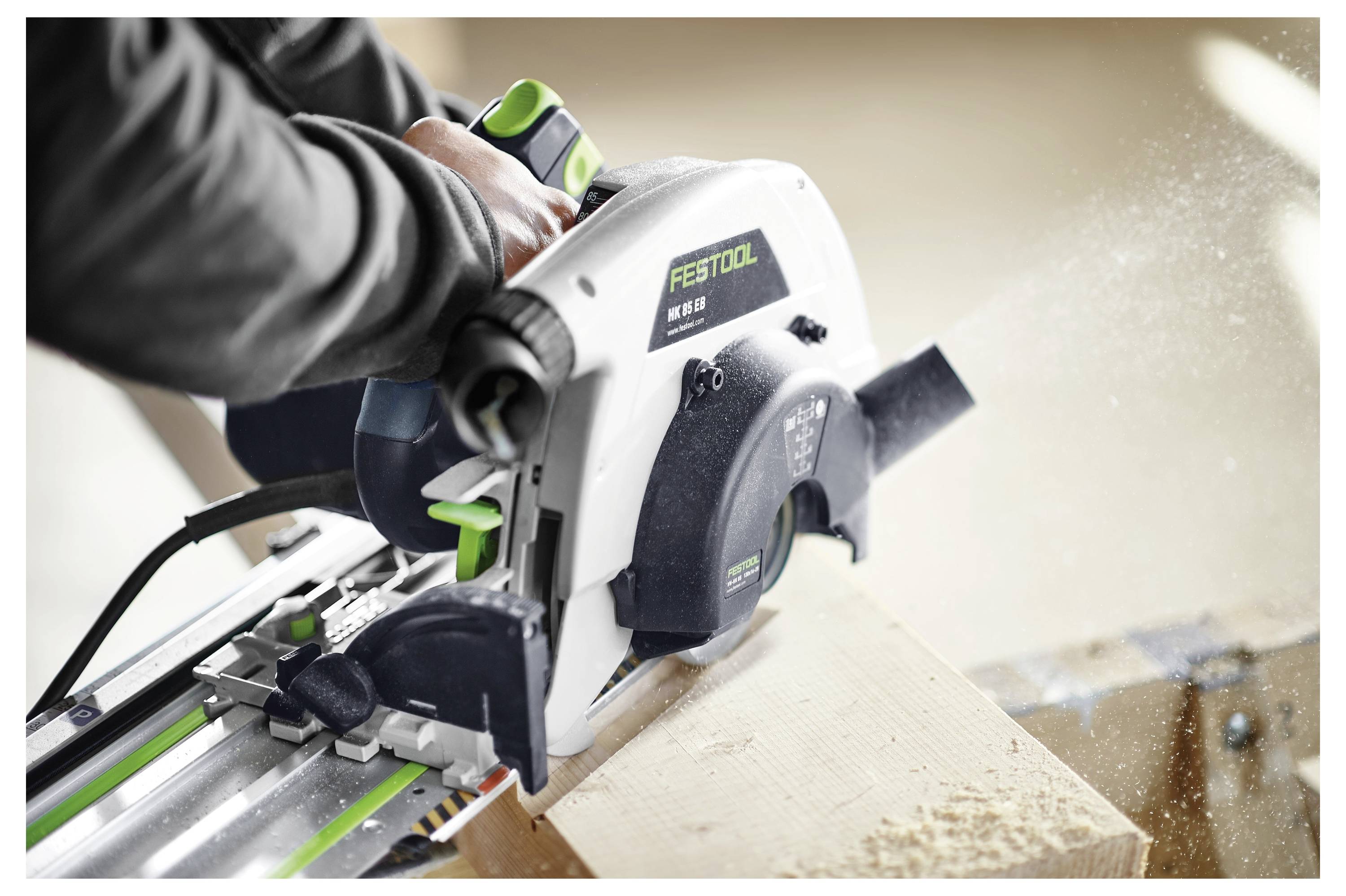 Eine Person verwendet eine Festool-Kreissäge, um ein Stück Holz zu schneiden, wobei Sägespäne emittiert werden.