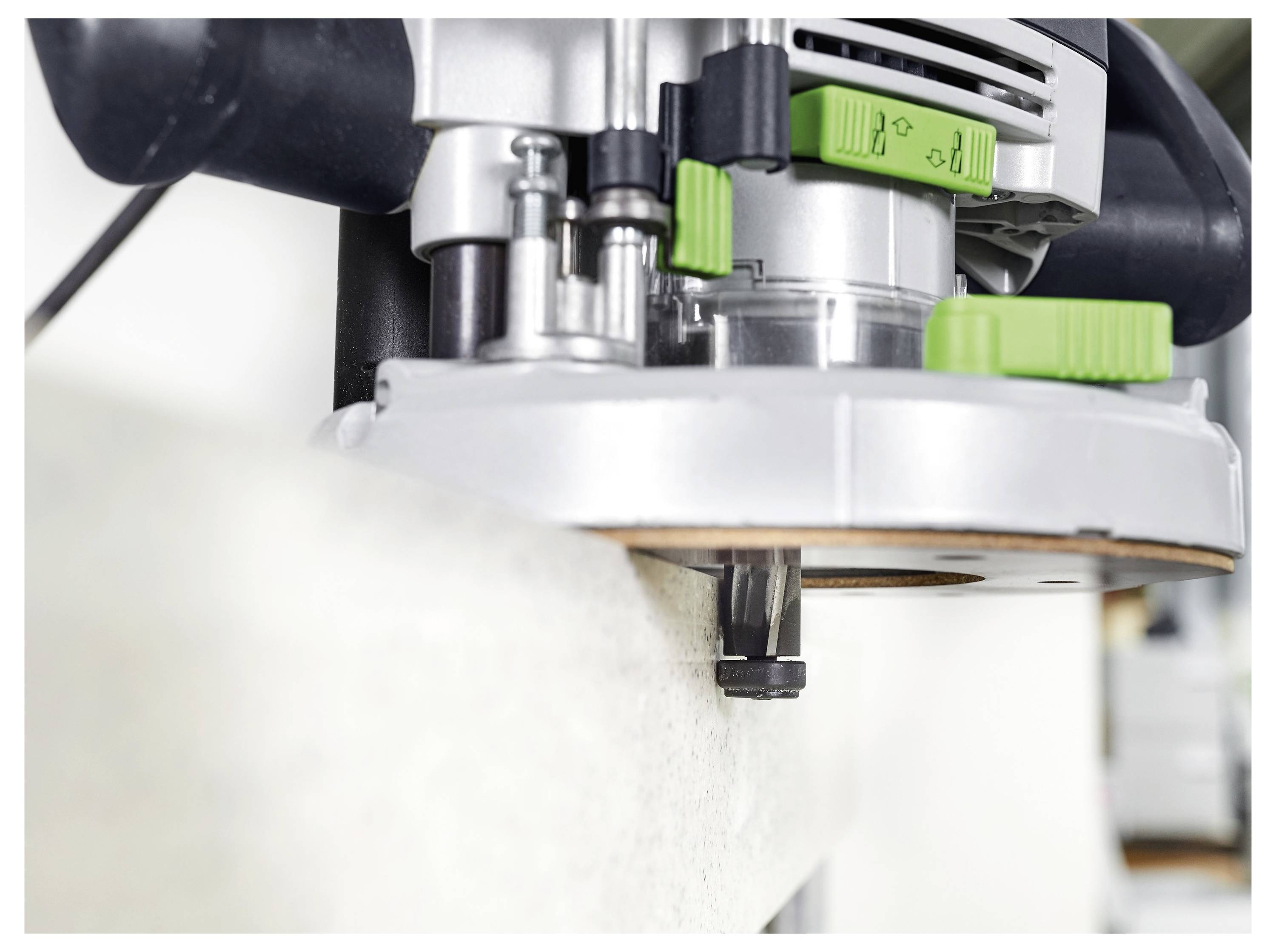 Eine Person schleifl eine weiße Wand in einem Renovierungsraum mit einer Festool-Maschine, die mit einem Staubsauger verbunden ist, während große Fenster im Hintergrund sichtbar sind.