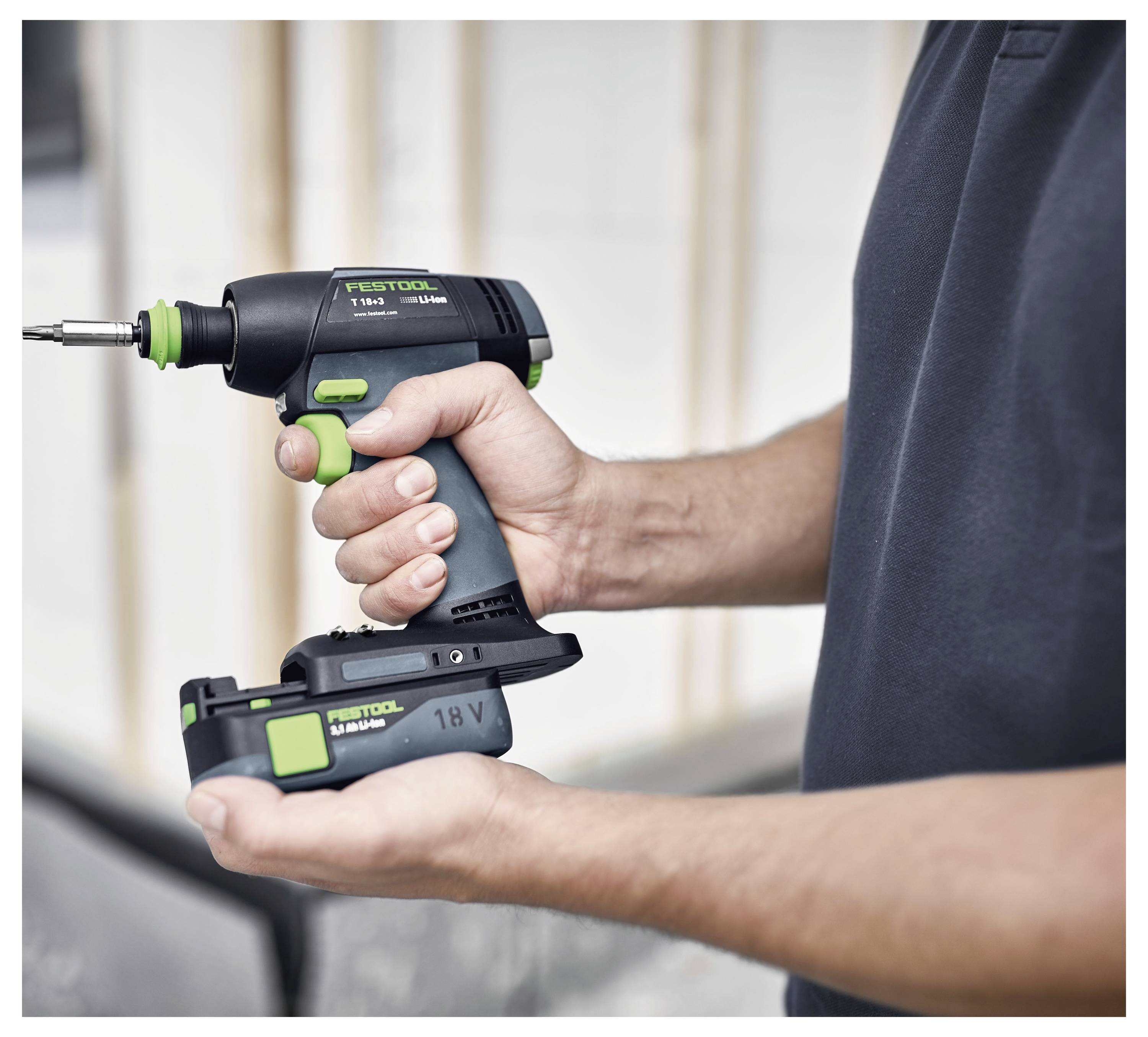 Eine Person hält einen kabellosen Bohrer mit grünen und schwarzen Akzenten, beschriftet mit „Festool 18V