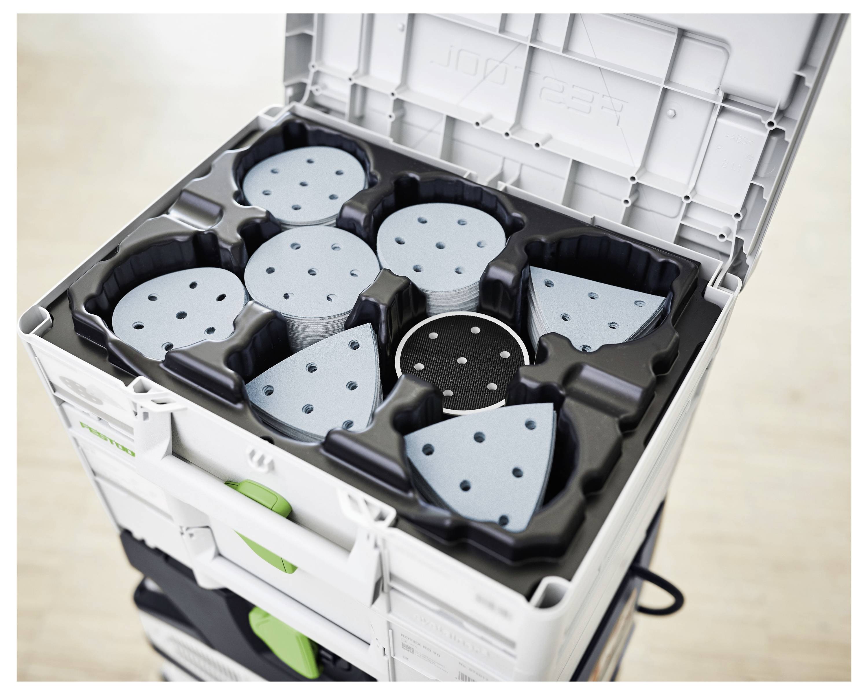 Eine offene Lagerkiste enthält Stapel von blauen und schwarzen kreisförmigen Schleifpapierblättern mit verschiedenen Körnungen, von denen jedes in geformten Fächern organisiert ist.