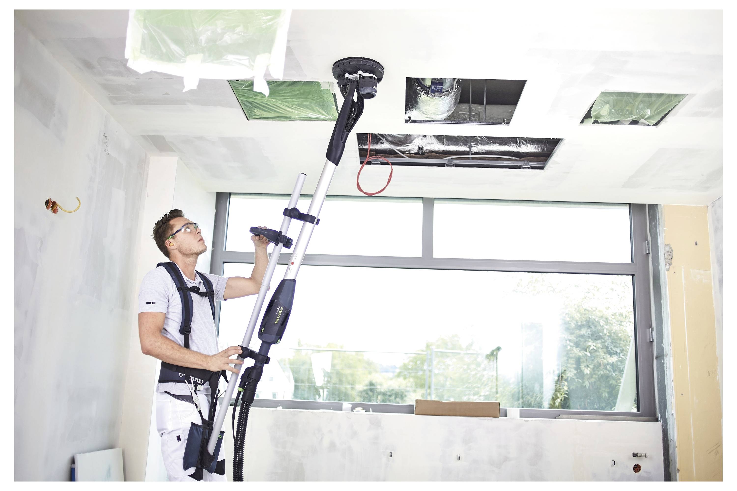 Hände halten eine Staubsaugerdüse und einen Schlauch, mit Fokus auf Griffigkeit und Manövrierbarkeit, vor einem einfarbigen Hintergrund.