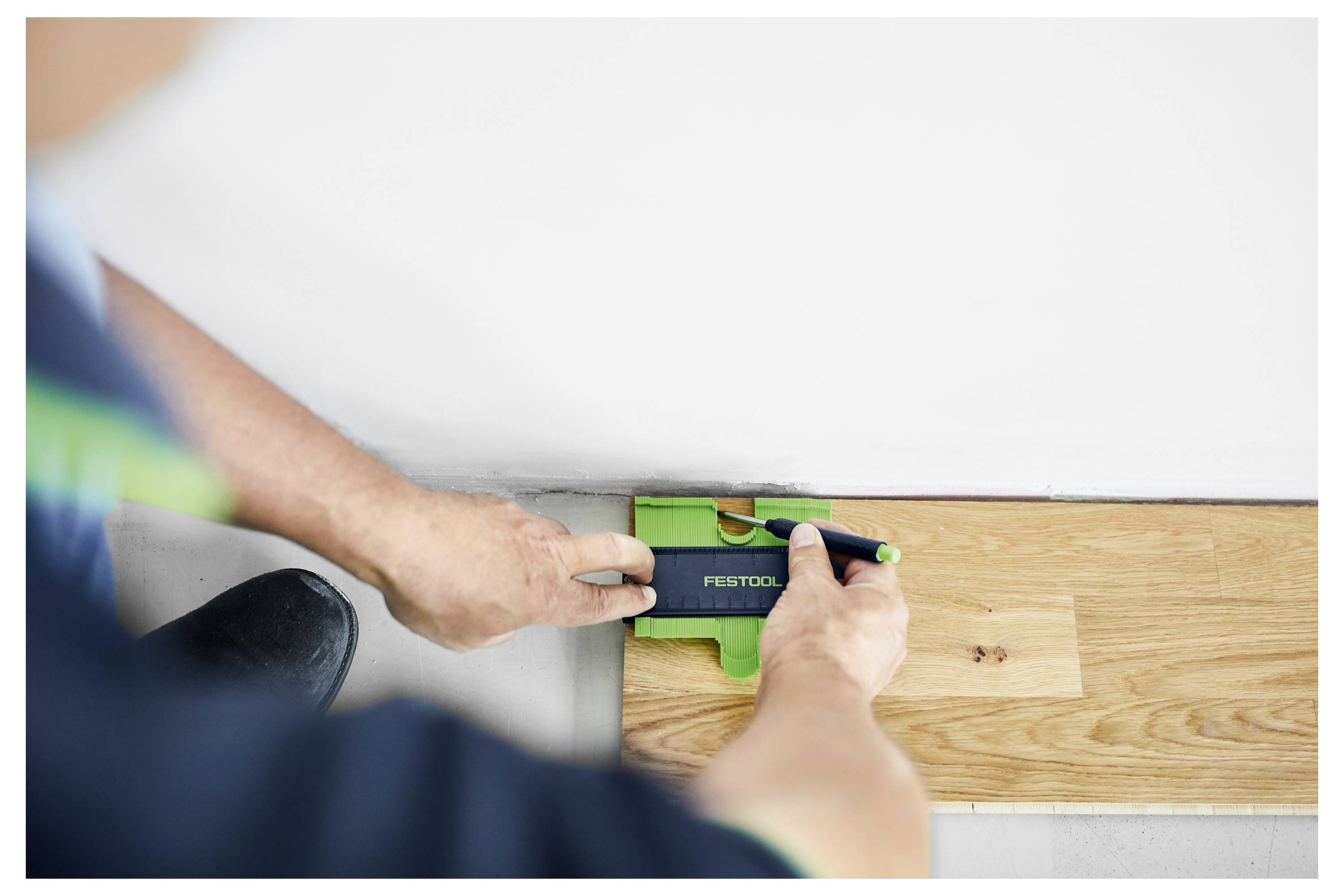 Eine Person nutzt eine Festool-Elektrosäge zum Schneiden von Beton. Die Säge ist in Nahaufnahme dargestellt und betont ihr Sägeblatt und die laufende Schneidaktion.