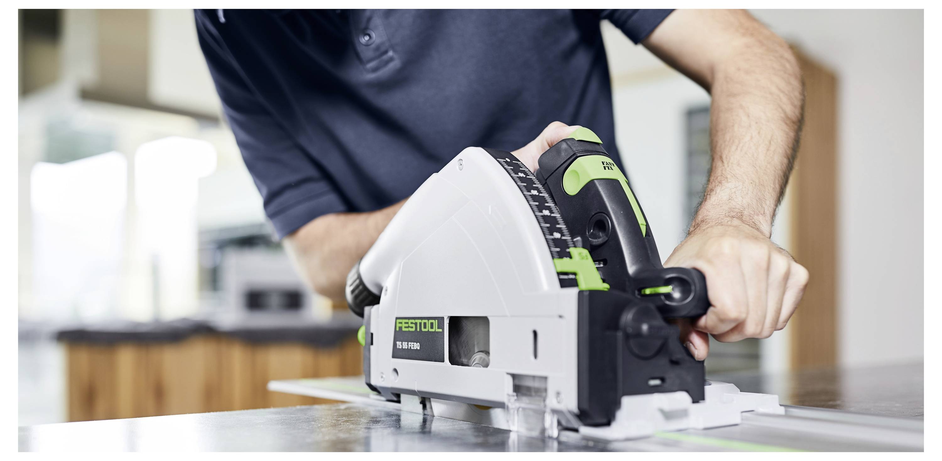 Eine Person verwendet eine Festool-Schienensäge zum Durchschneiden eines Materialbogens in Innenräumen. Der Fokus liegt auf dem Werkzeug und der Schneidaktion.