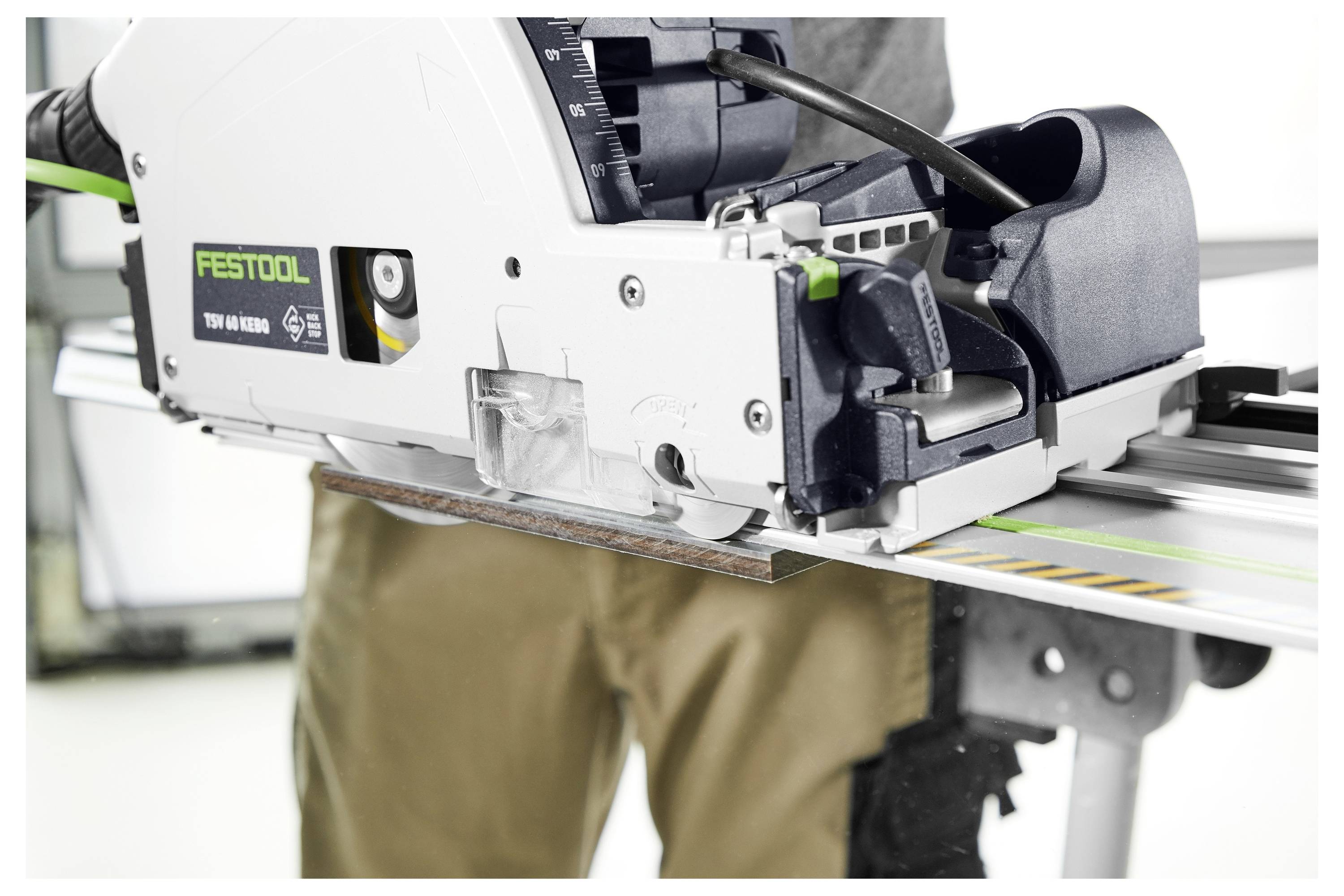 Ein Mann bedient eine Festool Tauchsäge und schneidet ein Stück Holz. Der Fokus liegt auf der Präzision und Funktionalität der Säge und hebt ihre Verwendung in der Holzbearbeitung hervor.