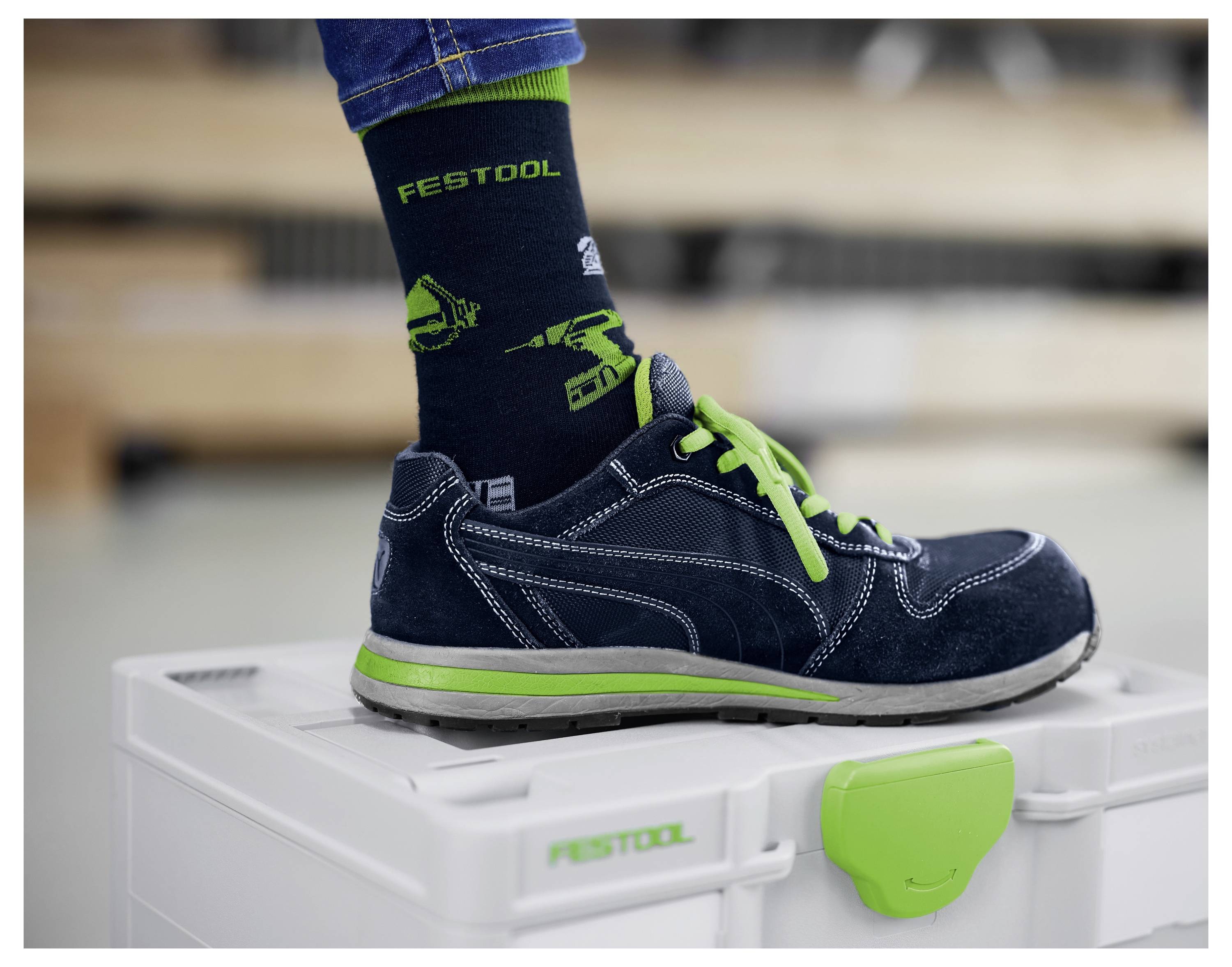 Ein Fuß in einem blauen Sneaker mit grünen Schnürsenkeln und einer „Festool