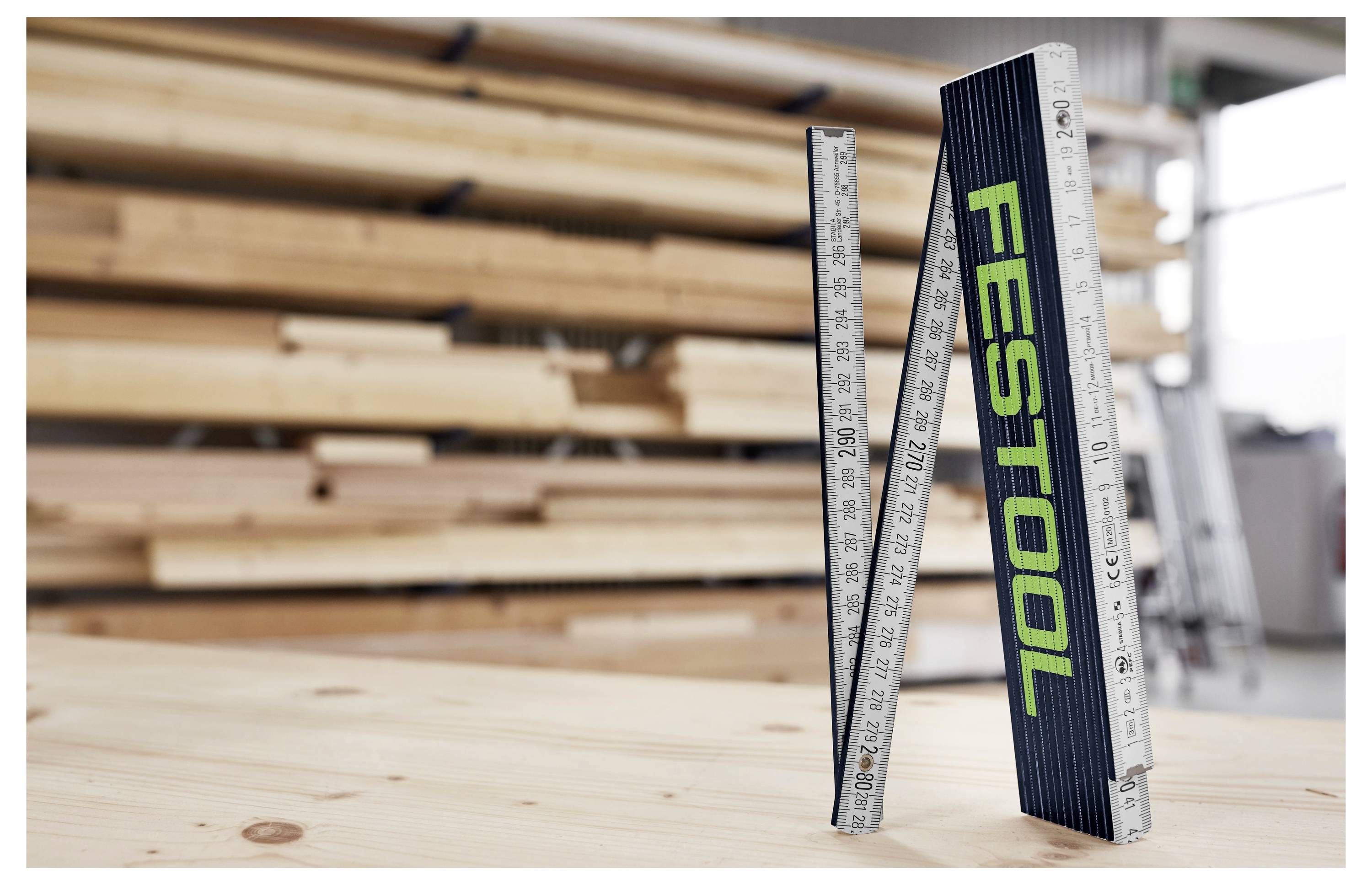 Person, die einen Elektroschrauber zum Mischen von Farbe auf einer Baustelle verwendet, trägt Handschuhe und Schutzkleidung vor einem Hintergrund von freiliegenden Backsteinmauern.