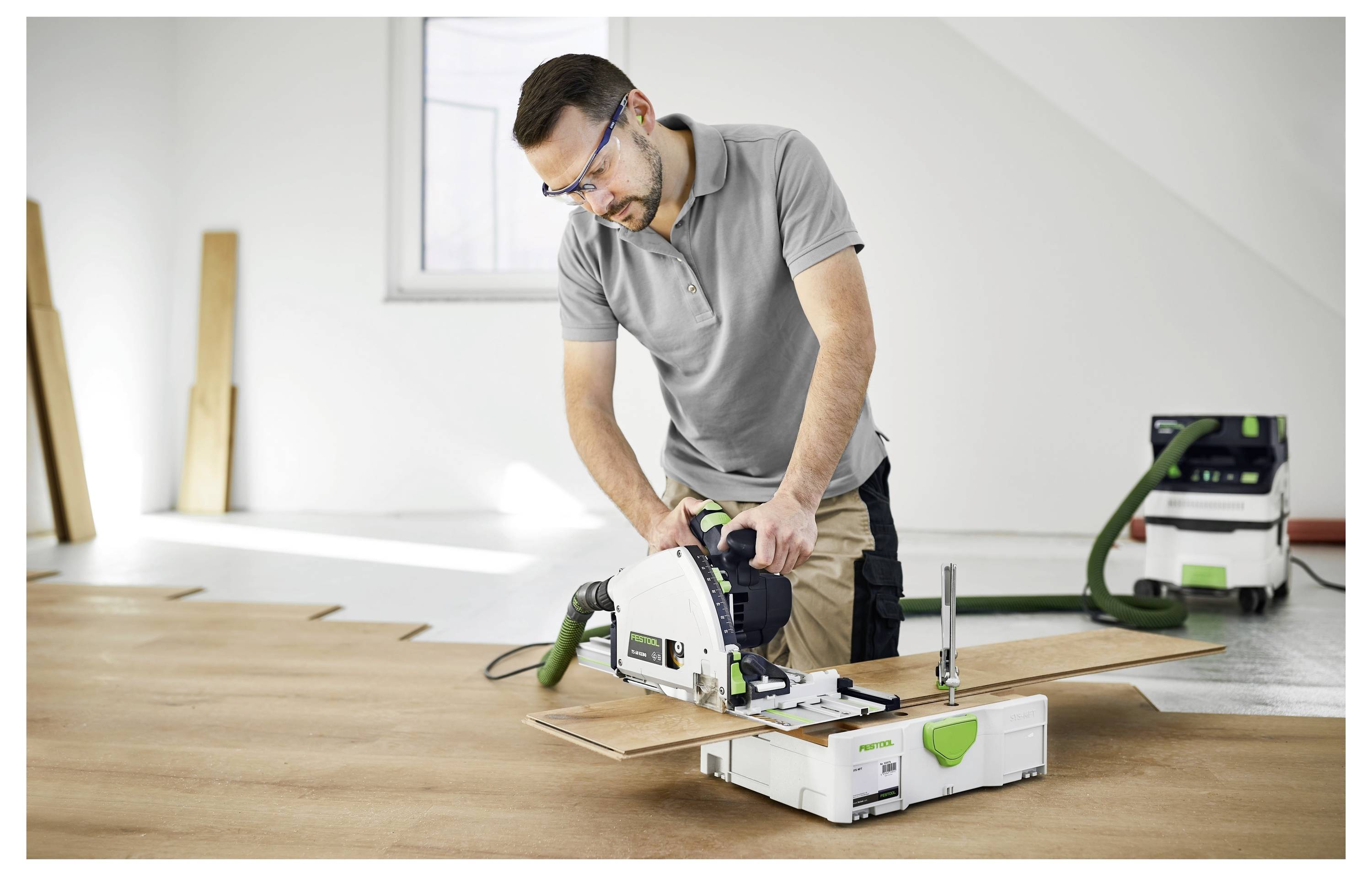 Ein Staubabscheider ist mit einem Schleifen verbunden, das von einem Arbeiter in Schutzausrüstung bedient wird, was einen Fokus auf Sicherheit und Sauberkeit anzeigt.