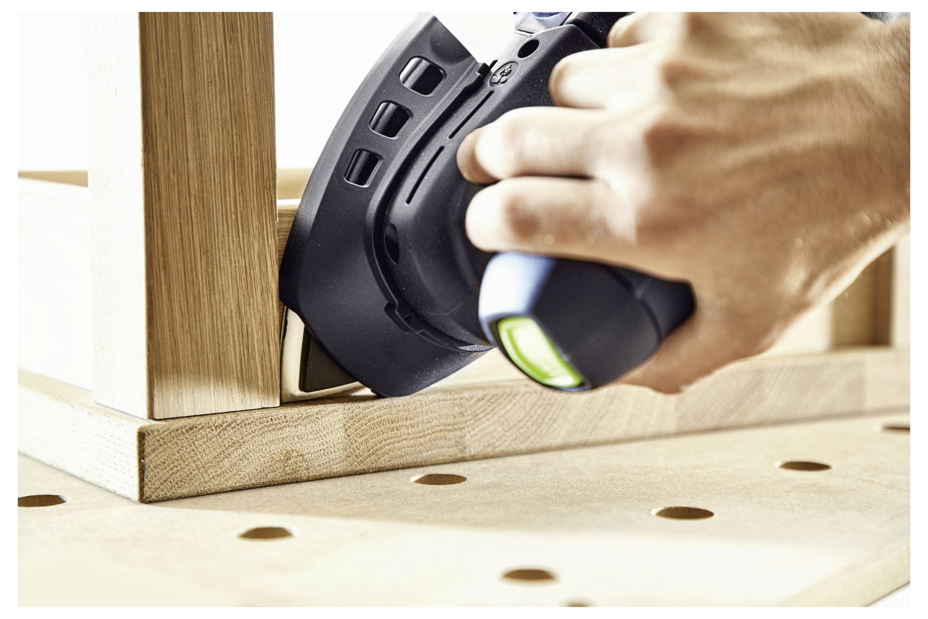 Eine Hand benutzt einen Elektroschleiffer an einer Tischkante aus Holz und glättet die Oberfläche.